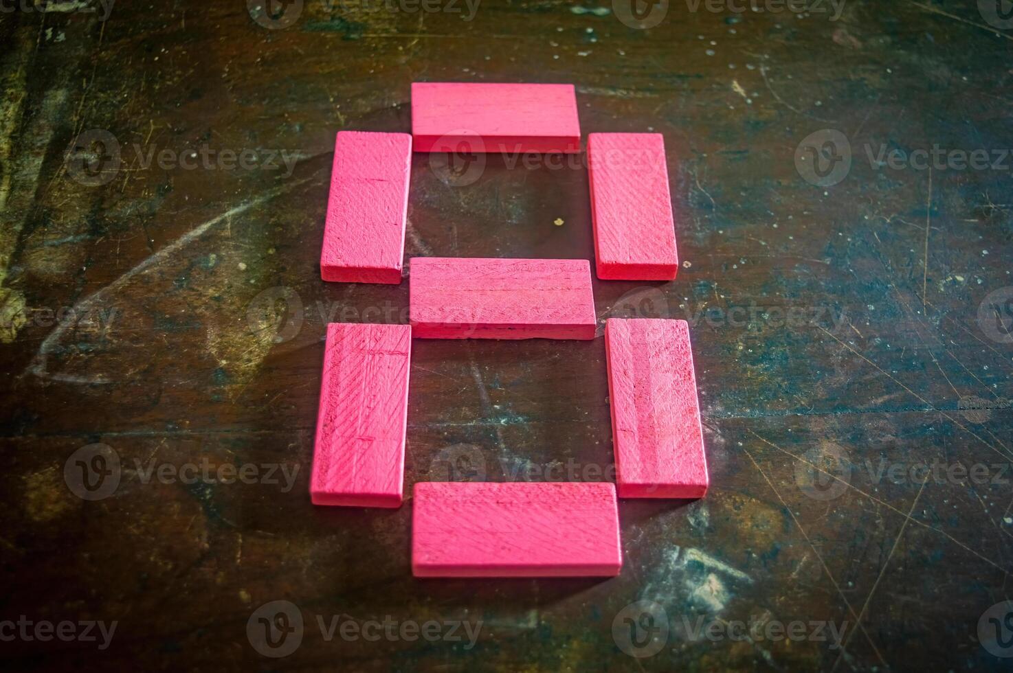 Red wooden blocks arranged in the shape of the number eight on a rustic wooden surface. Perfect for educational, numerical, or creative concepts photo