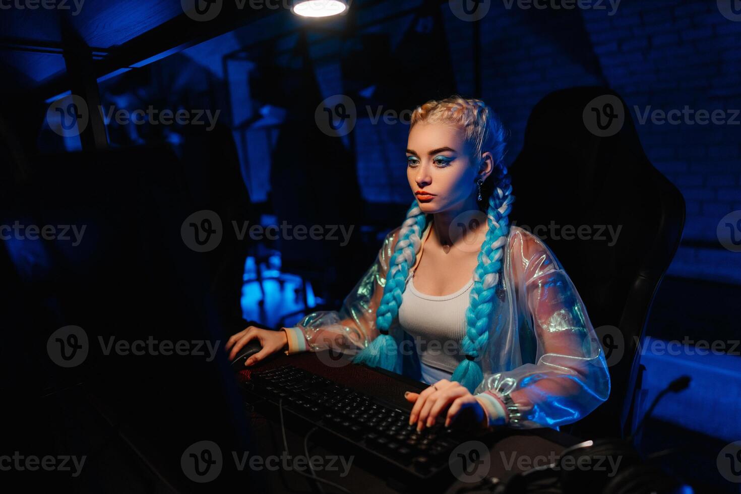 Young female blogger, gamer plays games on computer. Neon computer club. photo