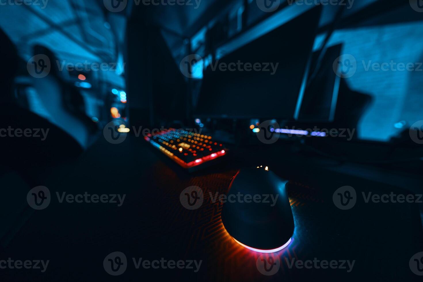 Computer setup featuring a colorful keyboard and mouse in a dimly lit room photo