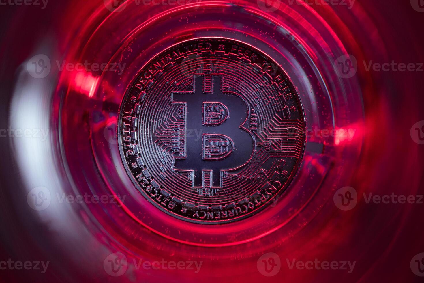Bitcoin at the bottom of the glass with water and red lights. photo