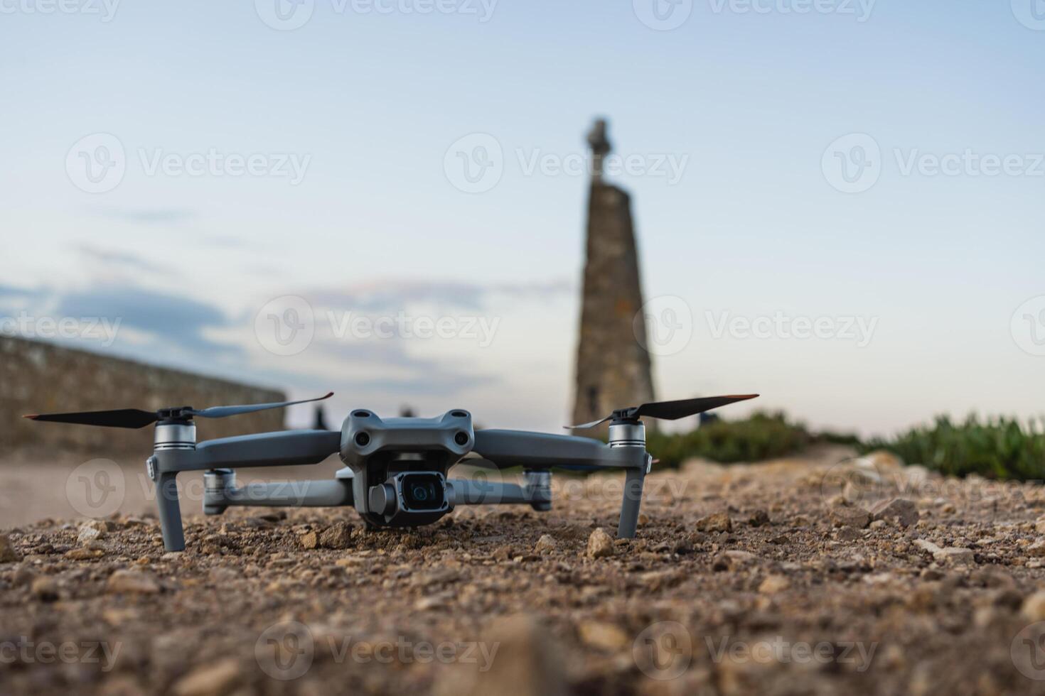 Drone rests on ground near historic monument at sunset in rural area photo