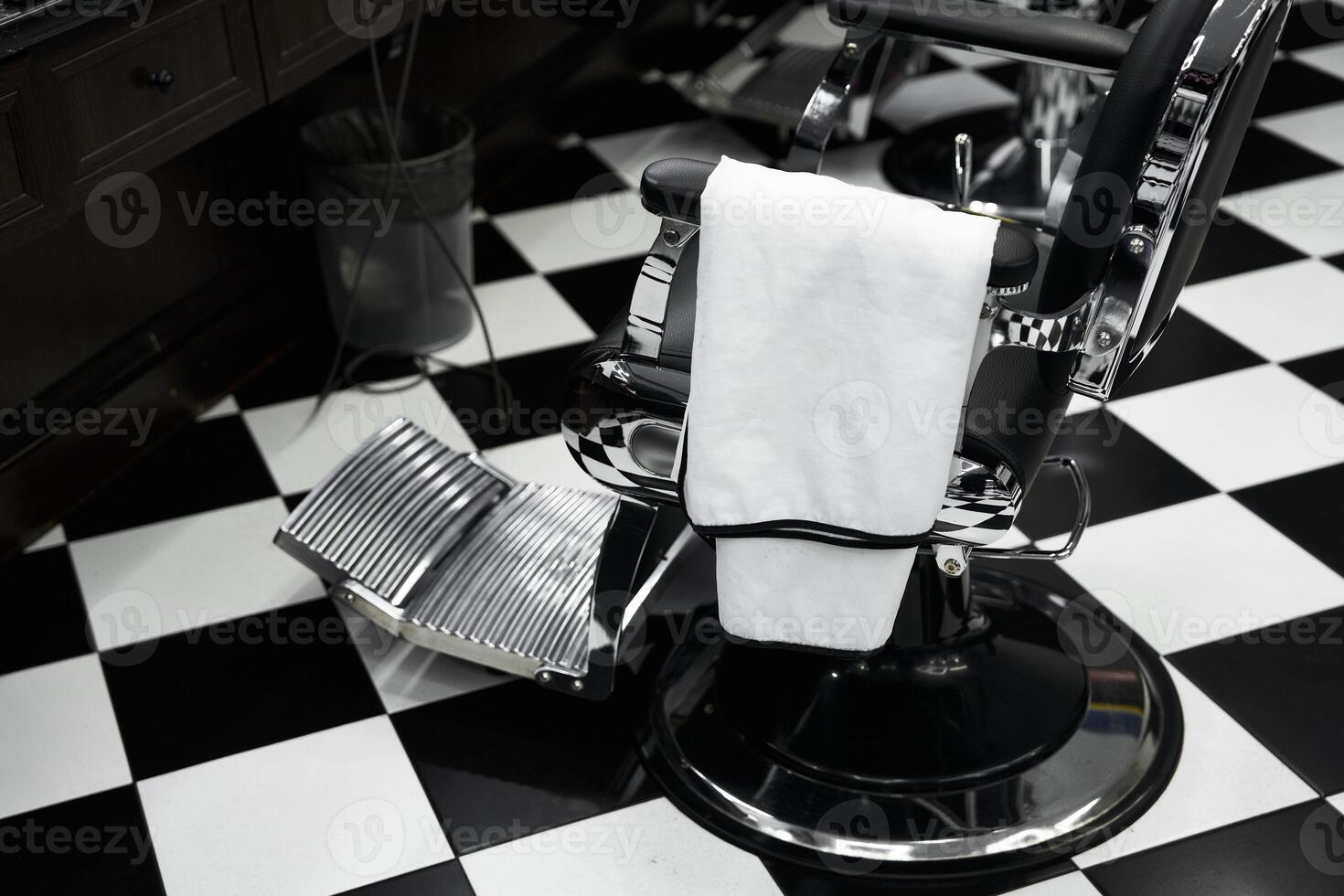 Black and white tiled barber shop with an empty barber chair waiting for clients photo