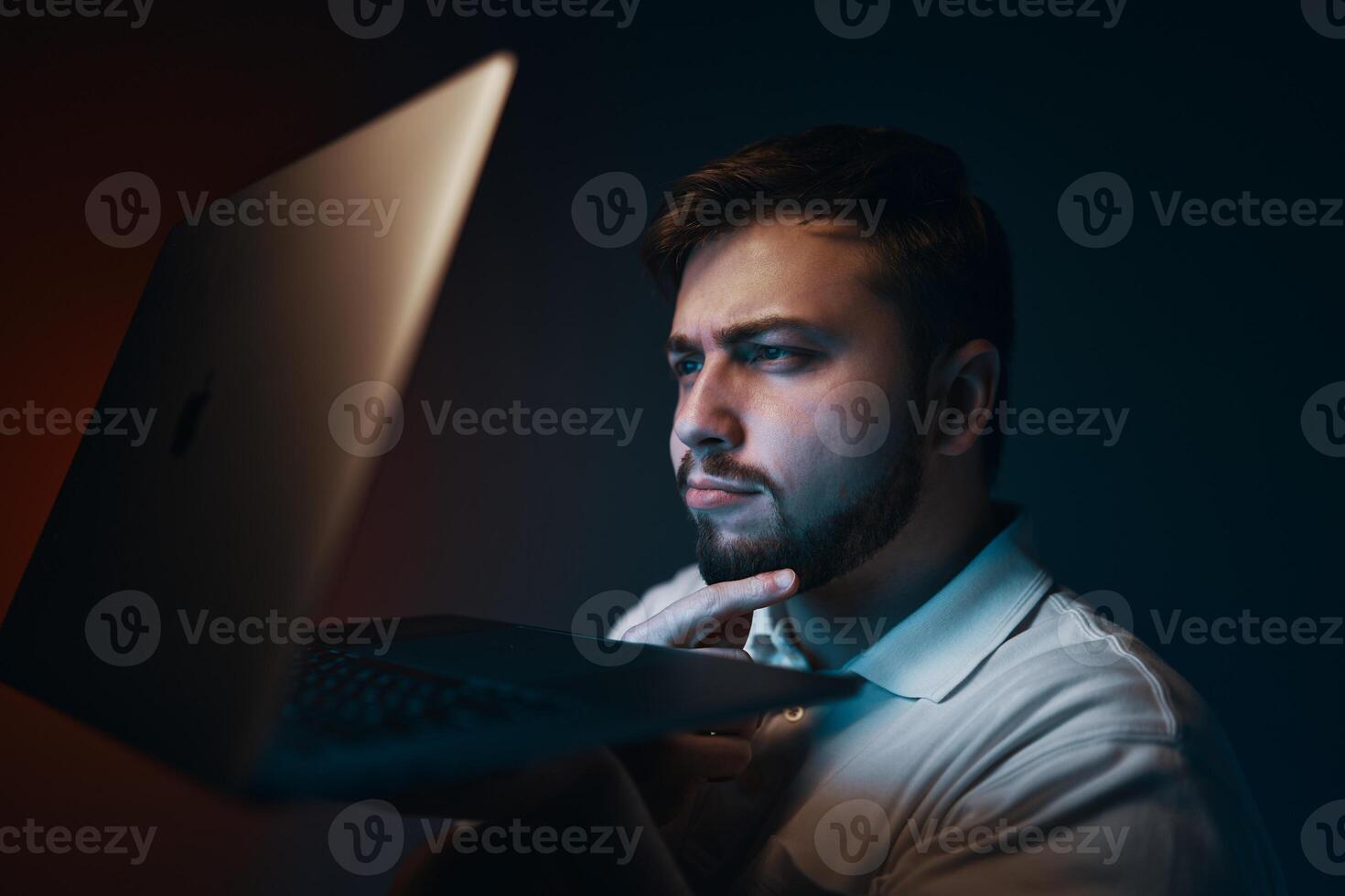 A man looks thoughtfully at the laptop screen. photo