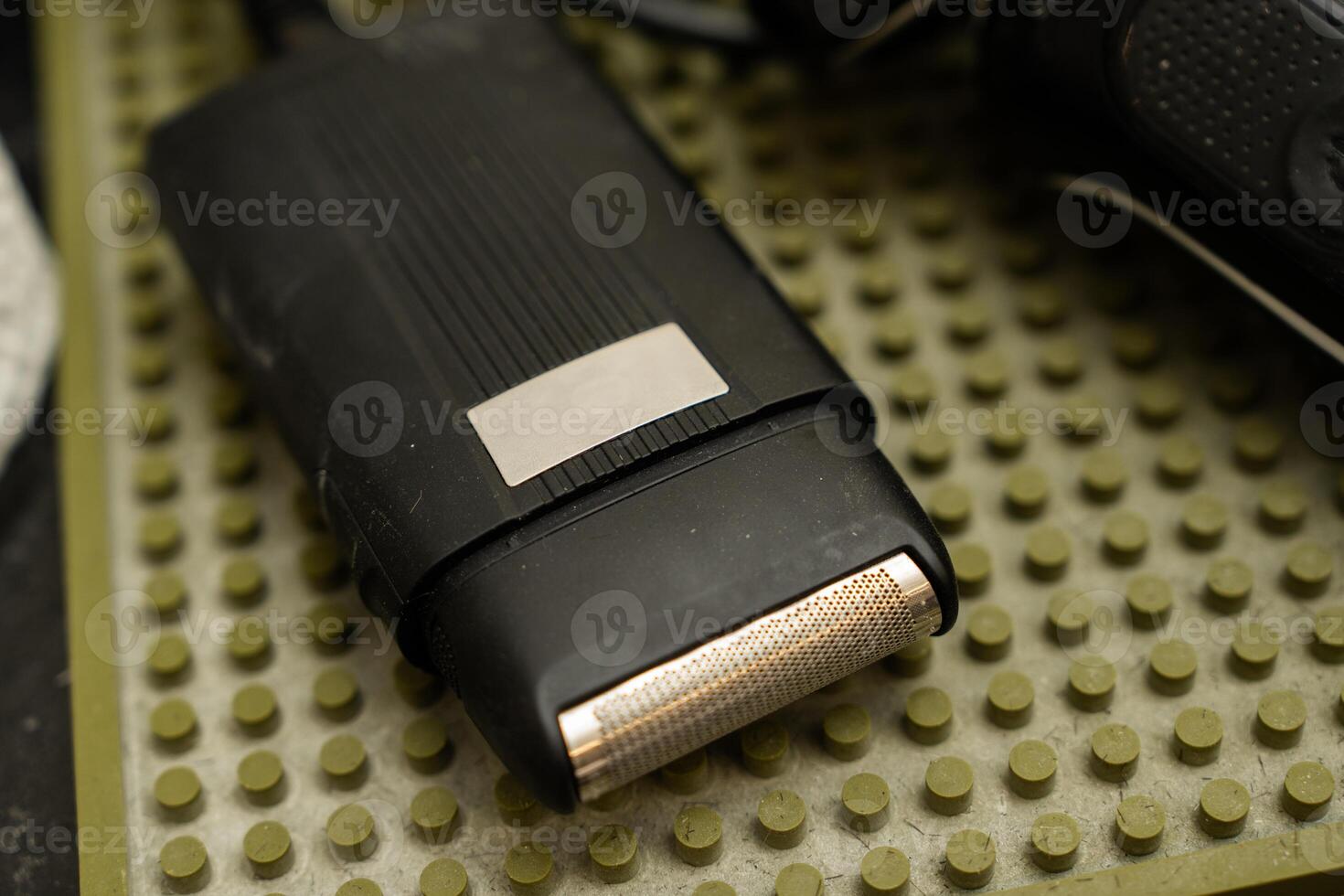 Close-up of an electric razor on a textured bathroom surface photo