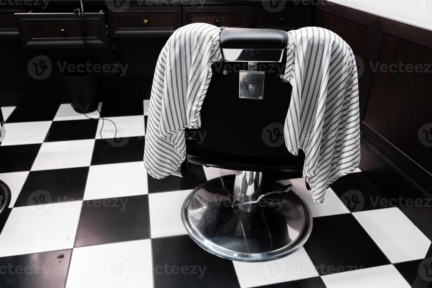 Barber chair with striped cape waiting for client in modern salon photo