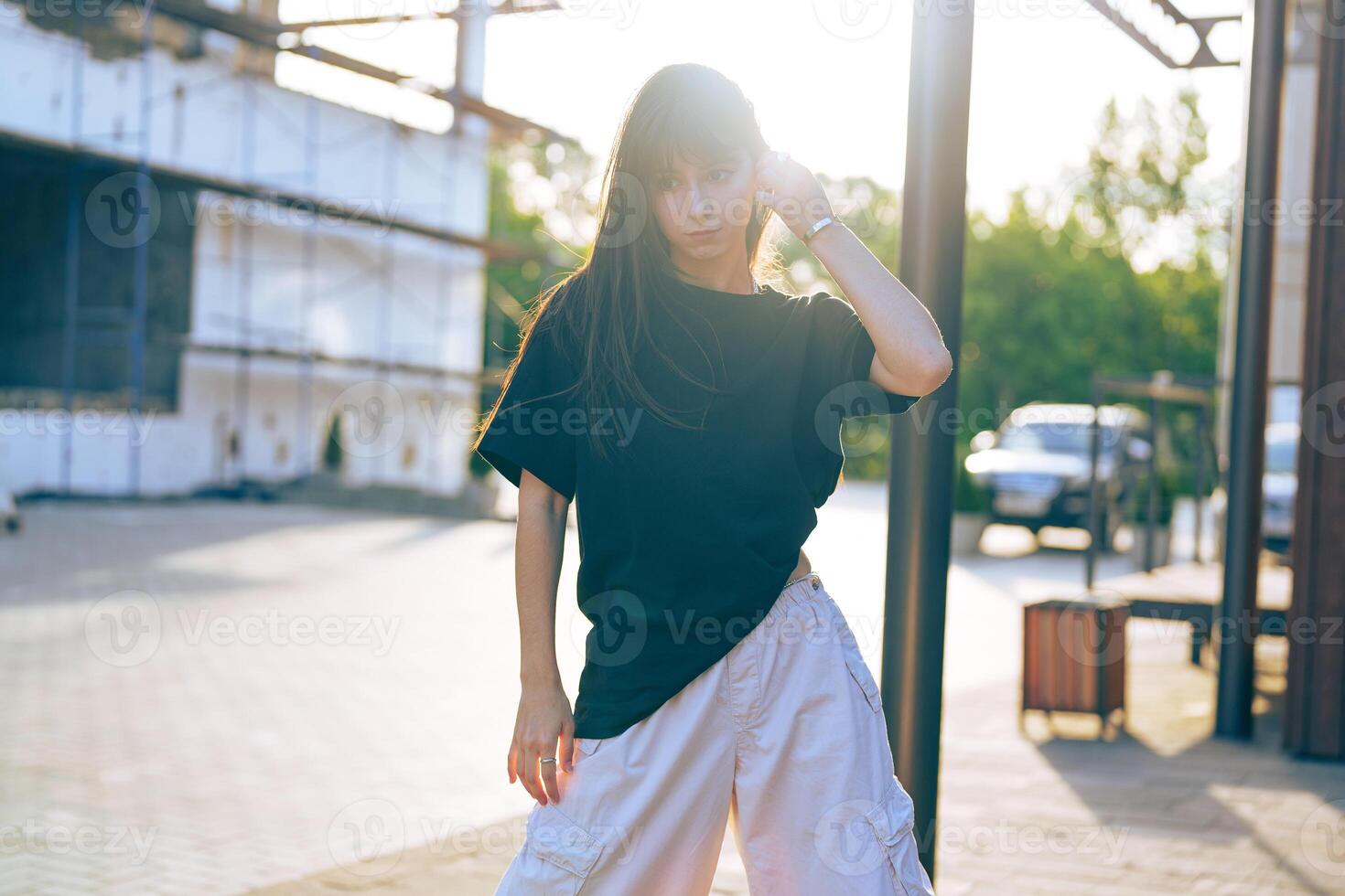 Stylish woman posing in urban setting at sunset wearing casual outfit and enjoying the warm evening light photo
