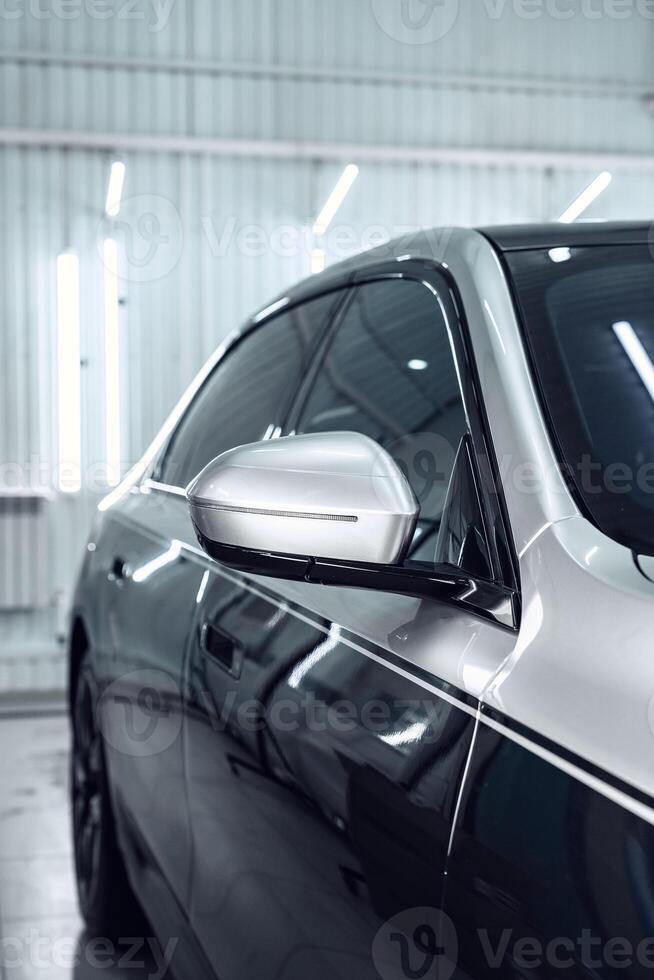 Sleek modern car with polished exterior showcases intricate side mirror design in well-lit workshop environment photo
