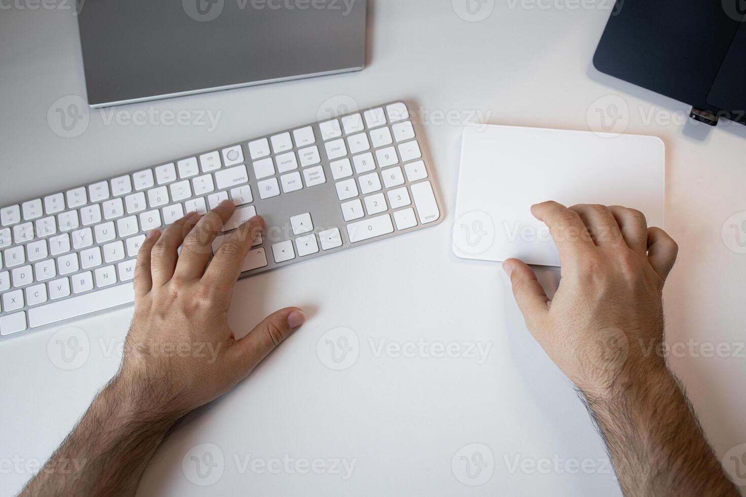 Male hands using trackpad and keyboard on white desk photo