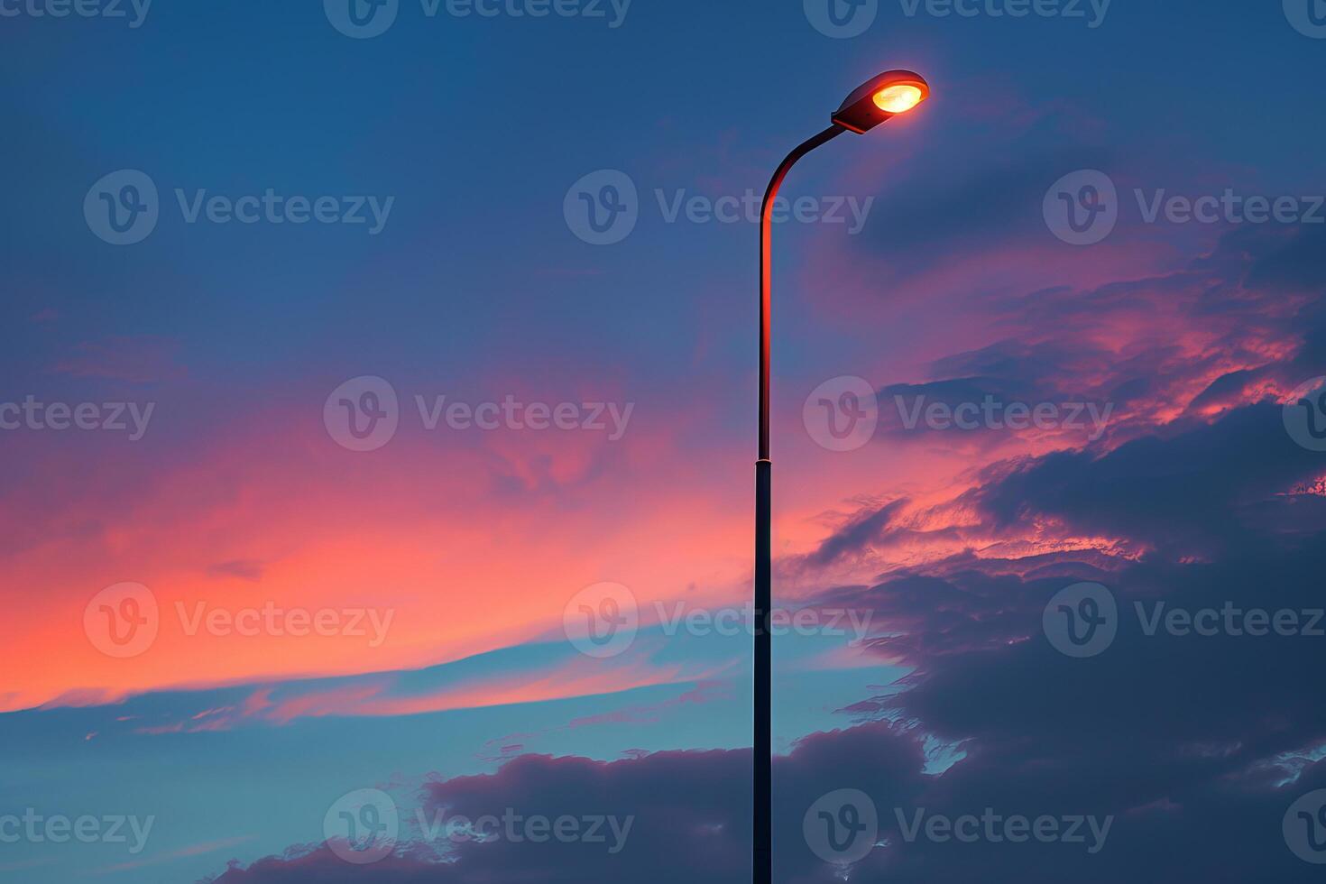 Street lamp illuminating a vibrant and colorful sunset sky photo