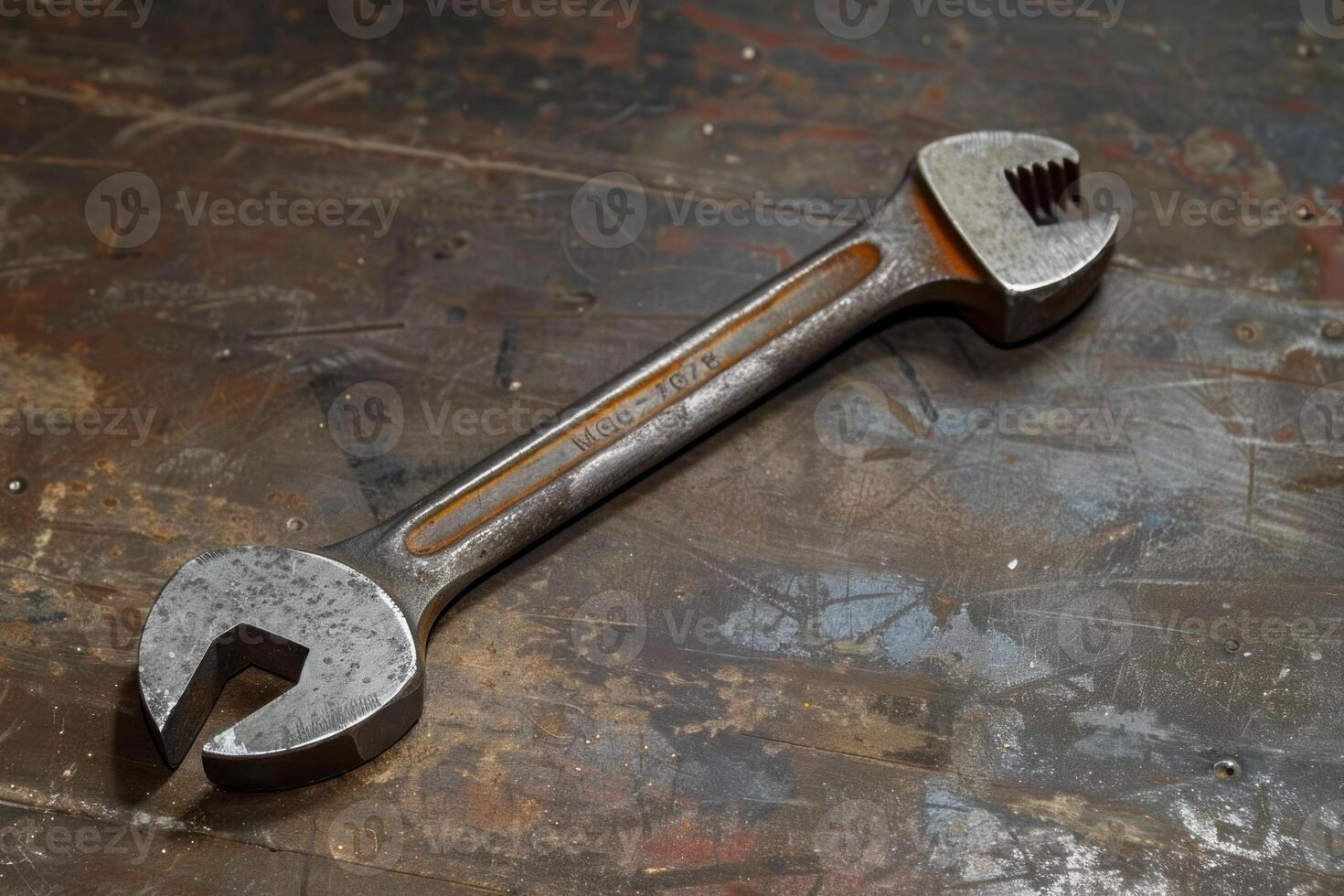 Old adjustable wrench lying on wooden workbench photo
