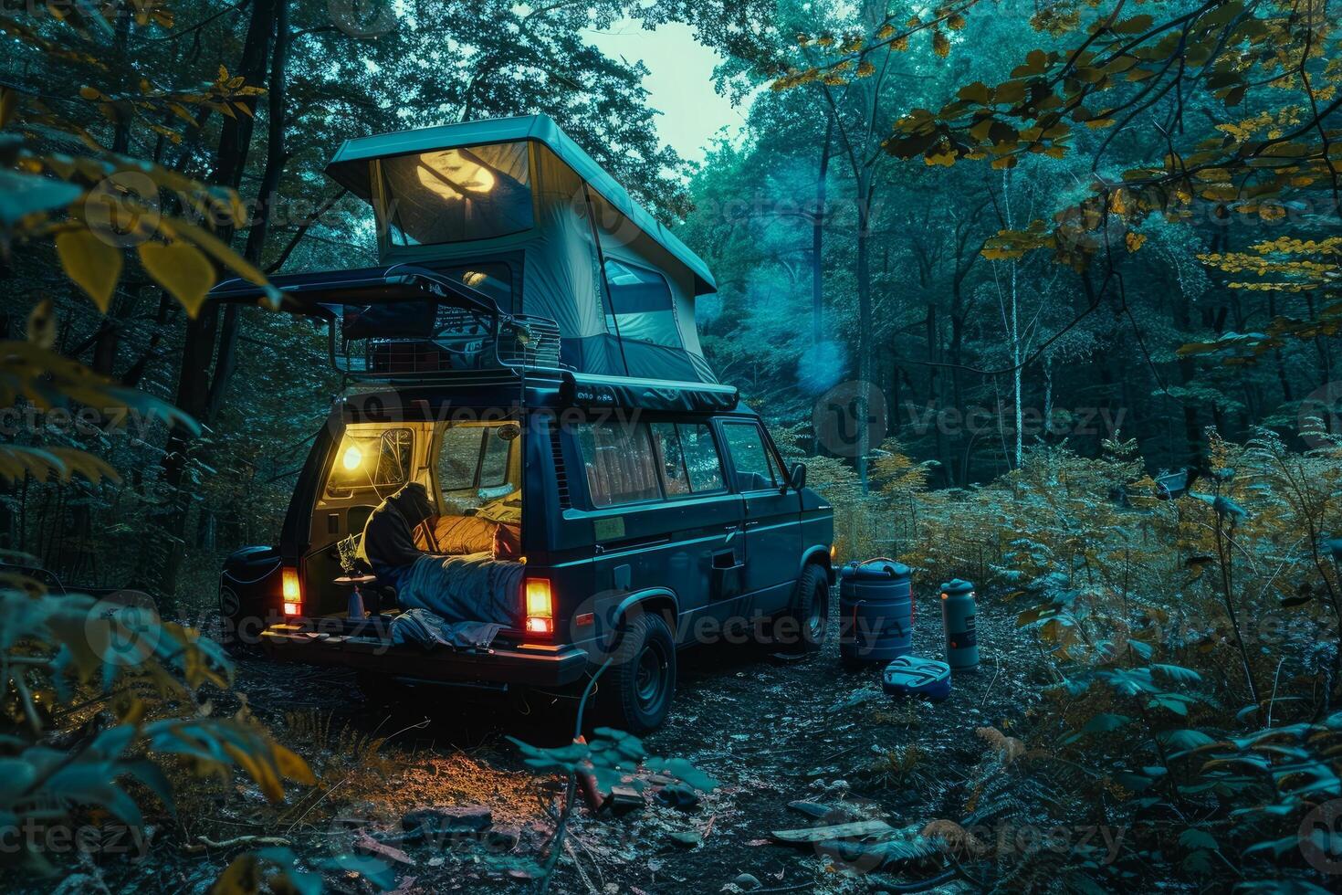 Camper van parked in forest with rooftop tent open and lit up at night photo