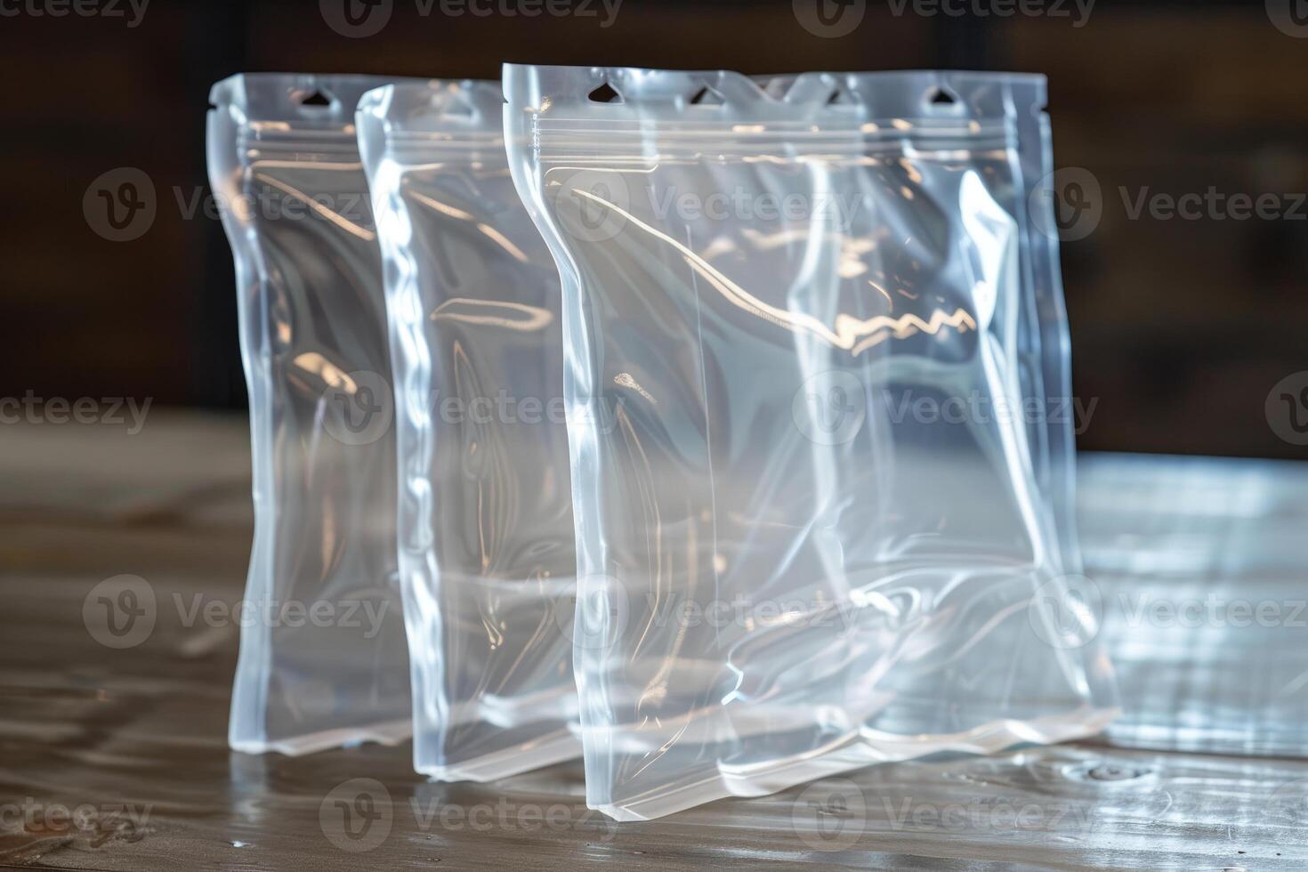 Three transparent plastic zipper bags standing on wooden surface photo