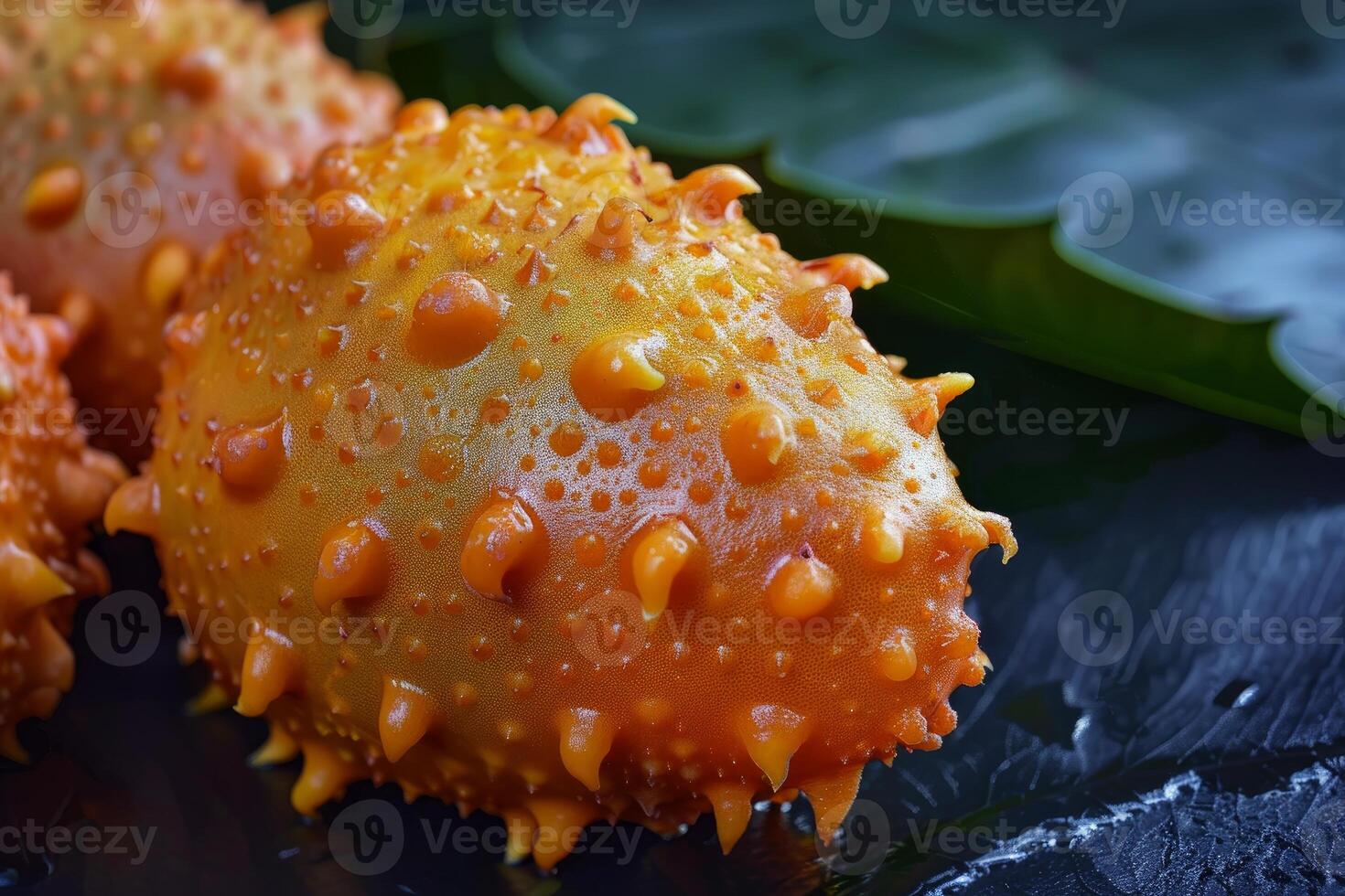 Kiwano melon resting on black slate with leaves in background photo