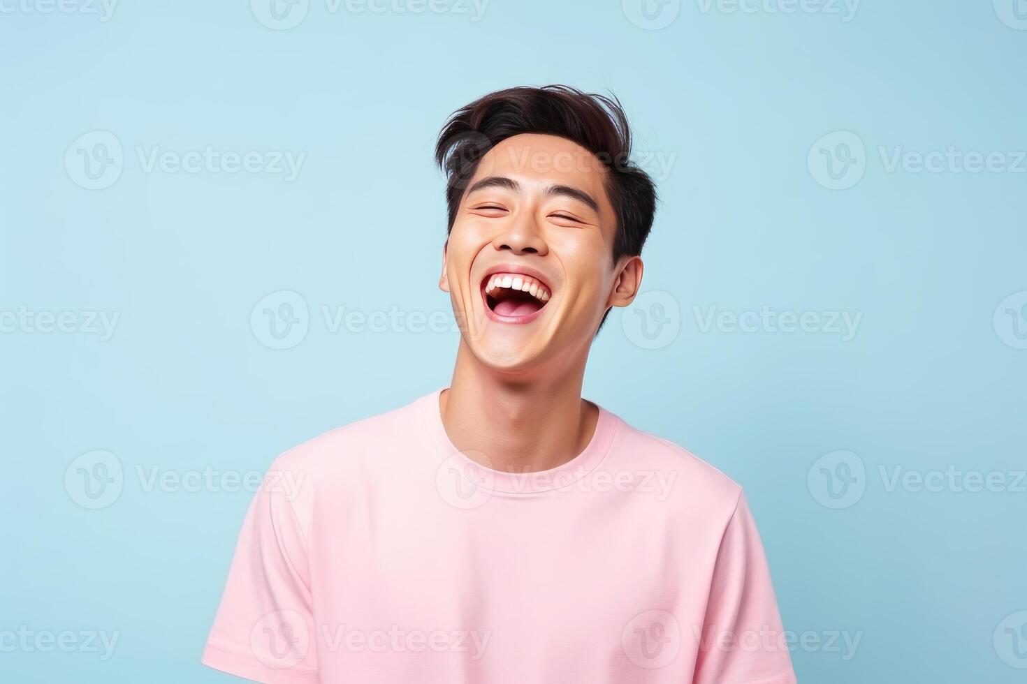 Young asian man laughing with open mouth on blue background photo