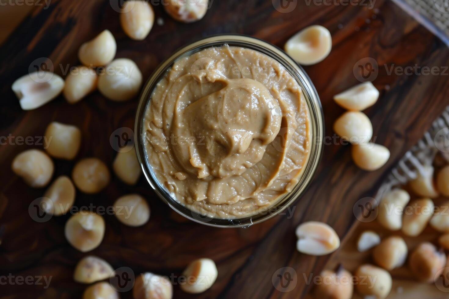 Macadamia nut butter surrounded by macadamia nuts on wooden board photo