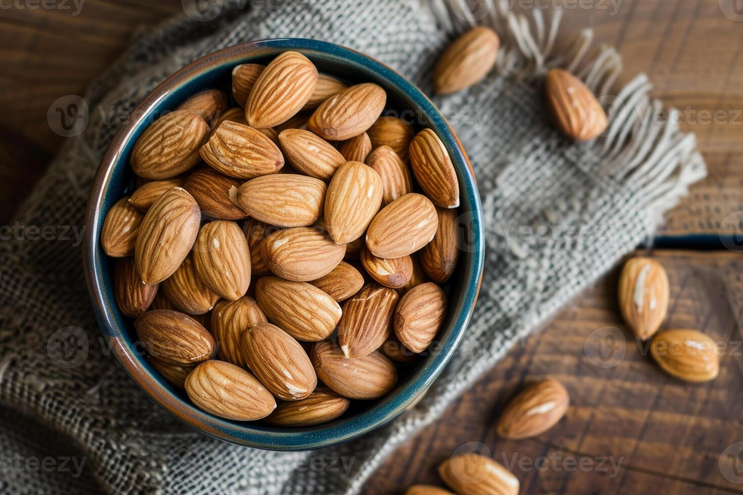 Bowl of almonds sitting on rustic wooden table with burlap cloth photo