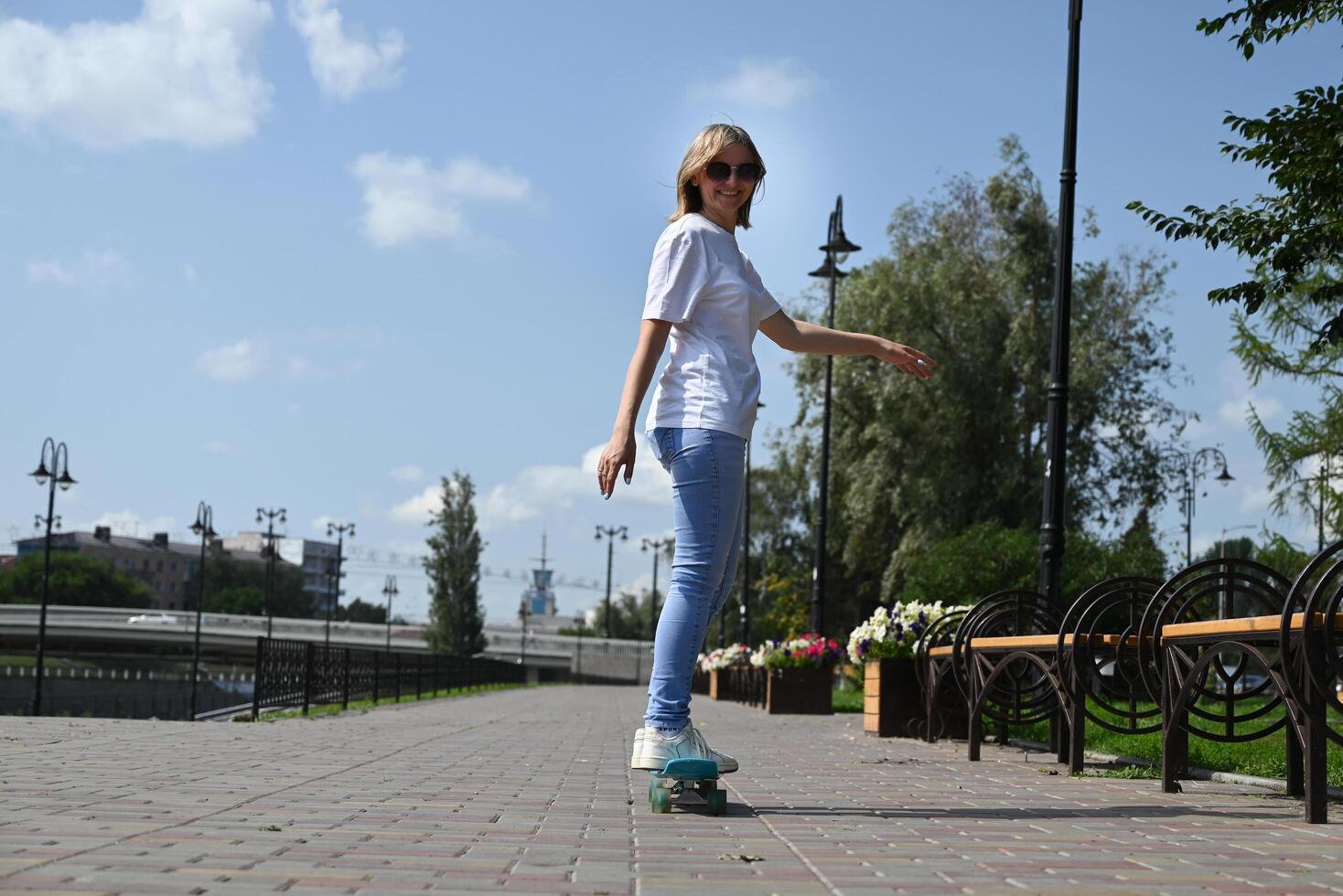 woman rides a skateboard on an empty road or highway. An ordinary city woman relaxing on a skateboard after work. The concept of a modern lifestyle photo