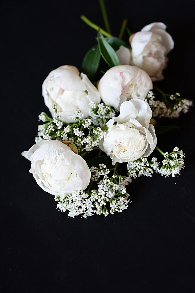Fresh white peonies on a black, dark background. A condolence card. Wedding date. An invitation to a holiday. Congratulation.An empty space for text. View from above. He was lying flat. photo