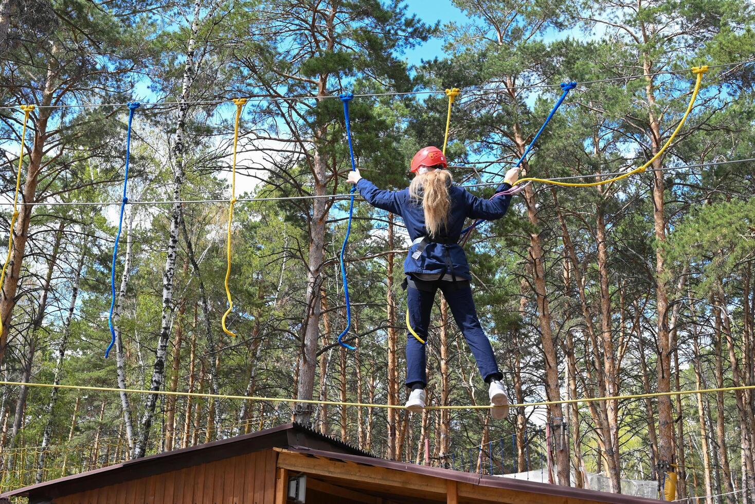 a teenage girl passes an obstacle in a rope park on a sunny day photo