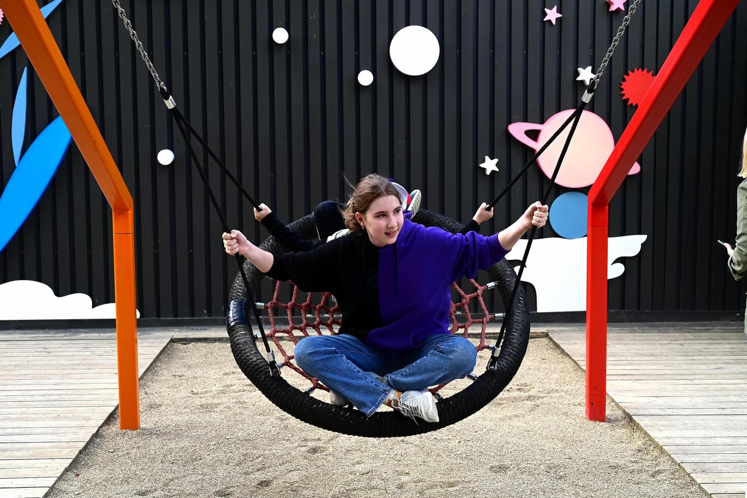 A girl swings on a round swing on the playground on a shunny day whith lought photo