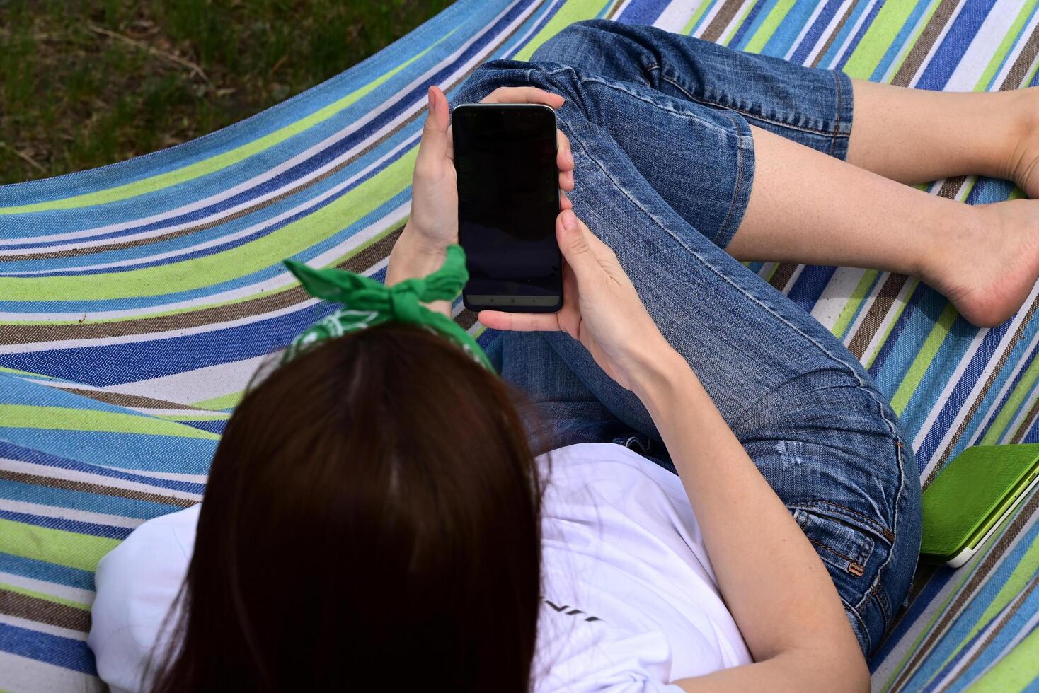 A young happy woman sitting in a park on the green grass photo