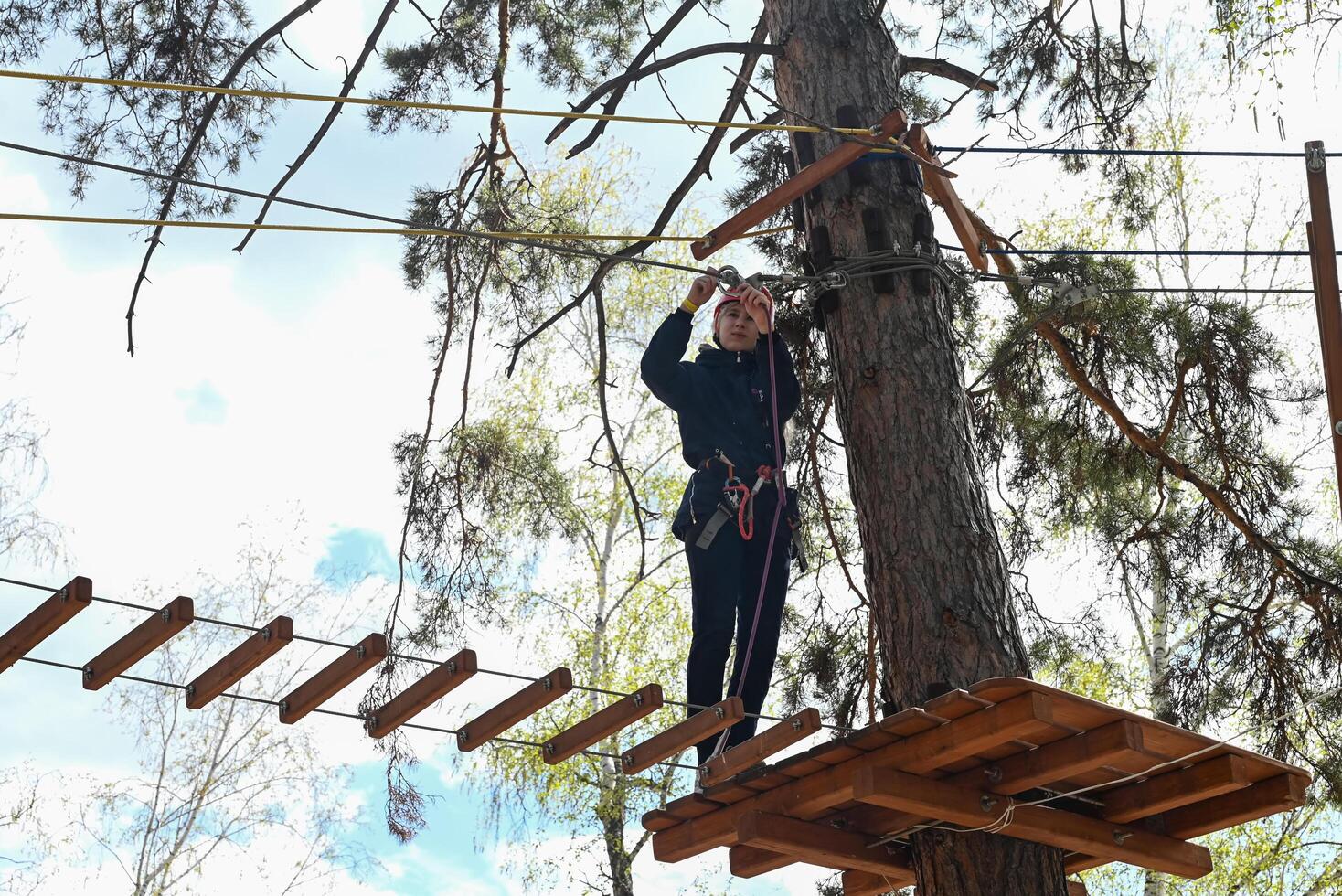 A picture of a person walking on a rope bridge course in a forest. photo
