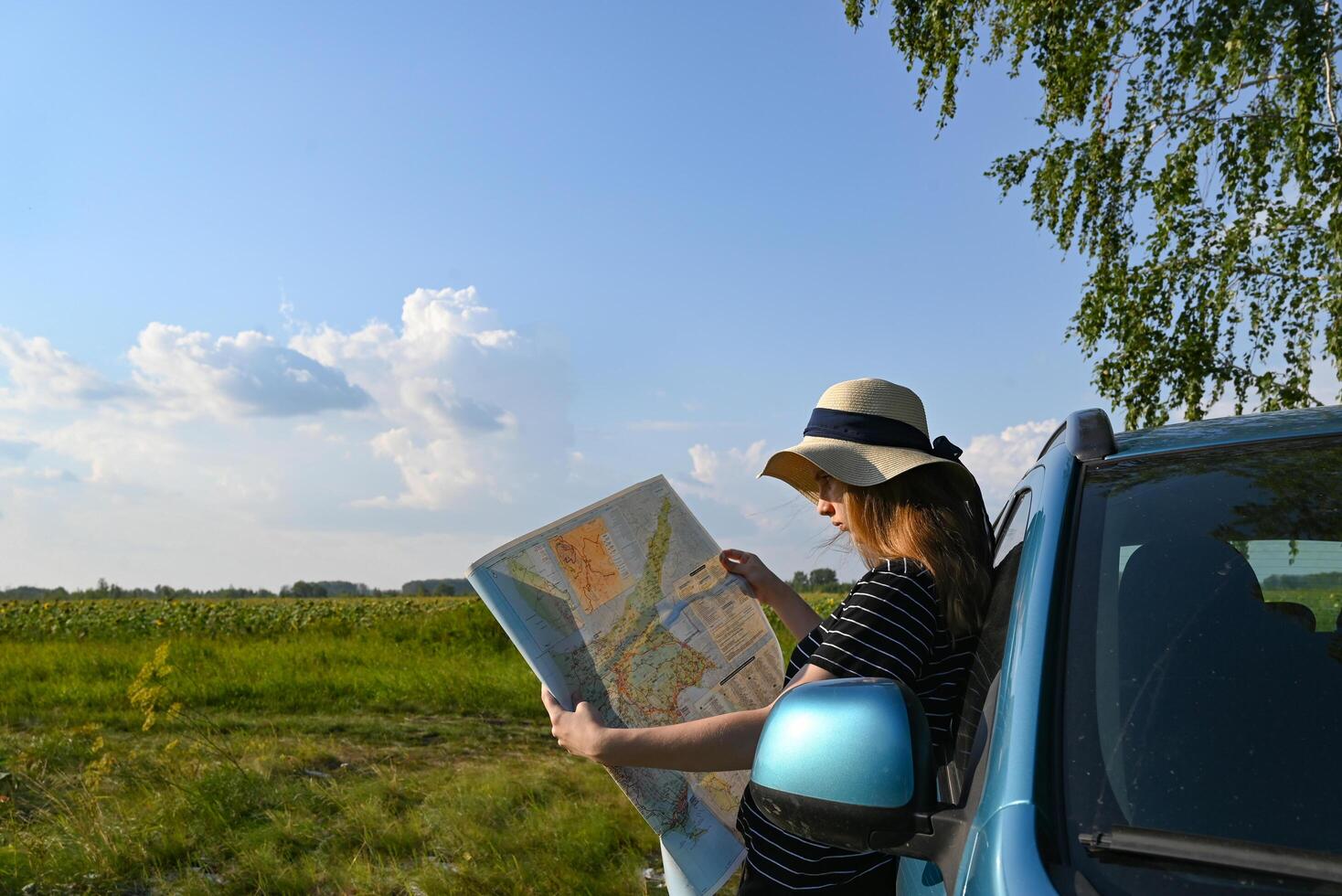 Rear view shot of couple driving on country road. Woman holding map and showing the route map to her boyfriend driving the car. Couple on a road trip. photo