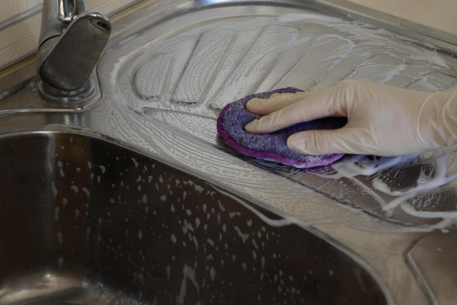 A woman in rubber gloves cleans the sink with detergent On a beautiful day photo