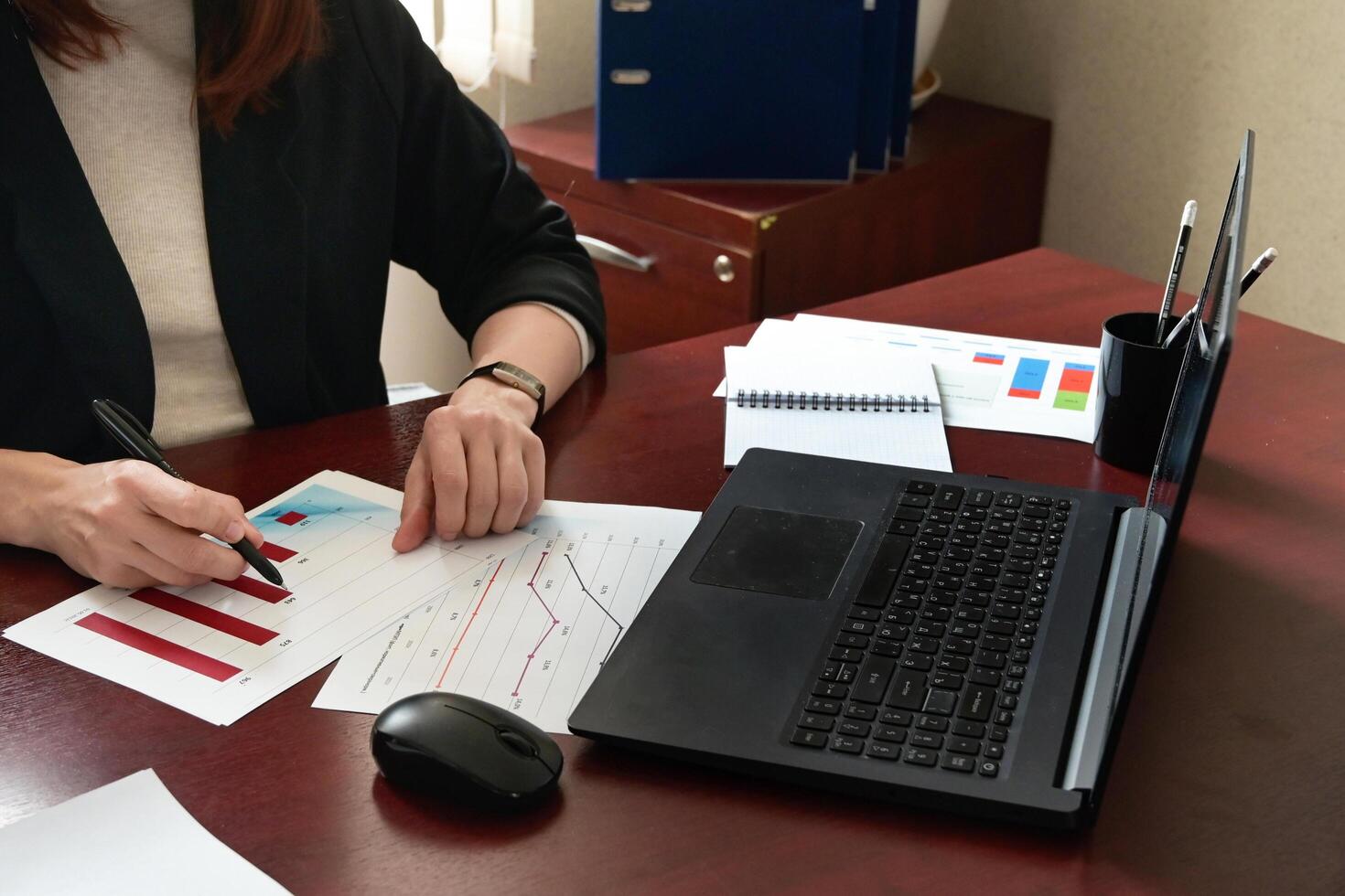 Rear view of female financial manager drawing various charts and schemes on wall in office photo