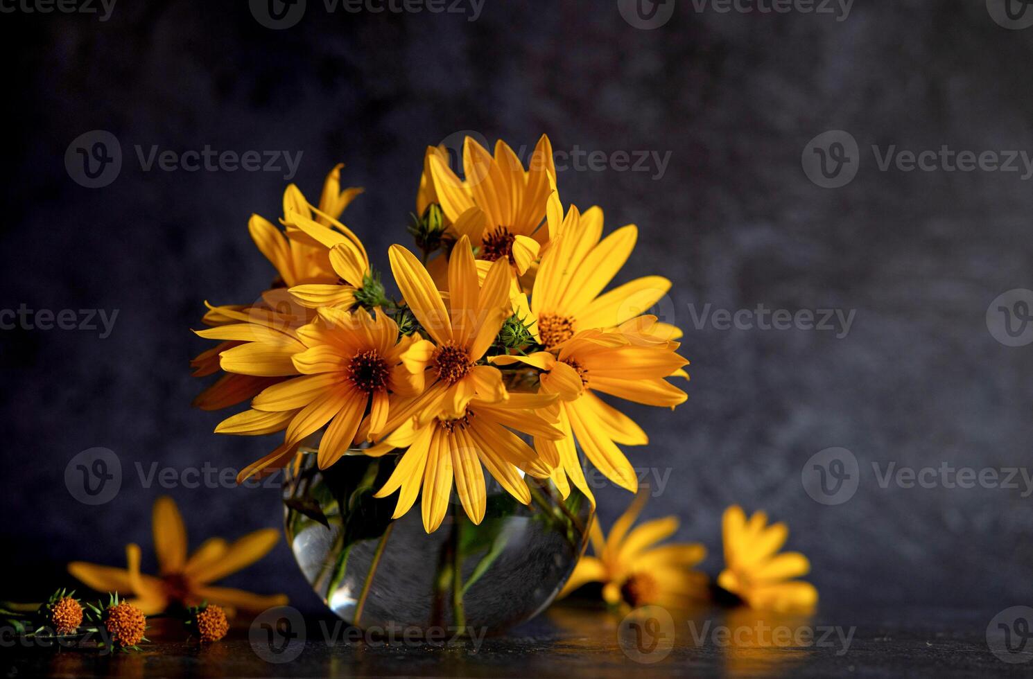 Against a dark canvas, vibrant yellow flowers and scattered petals frame a blank card and envelope, creating a scene of invitation and natural beauty photo