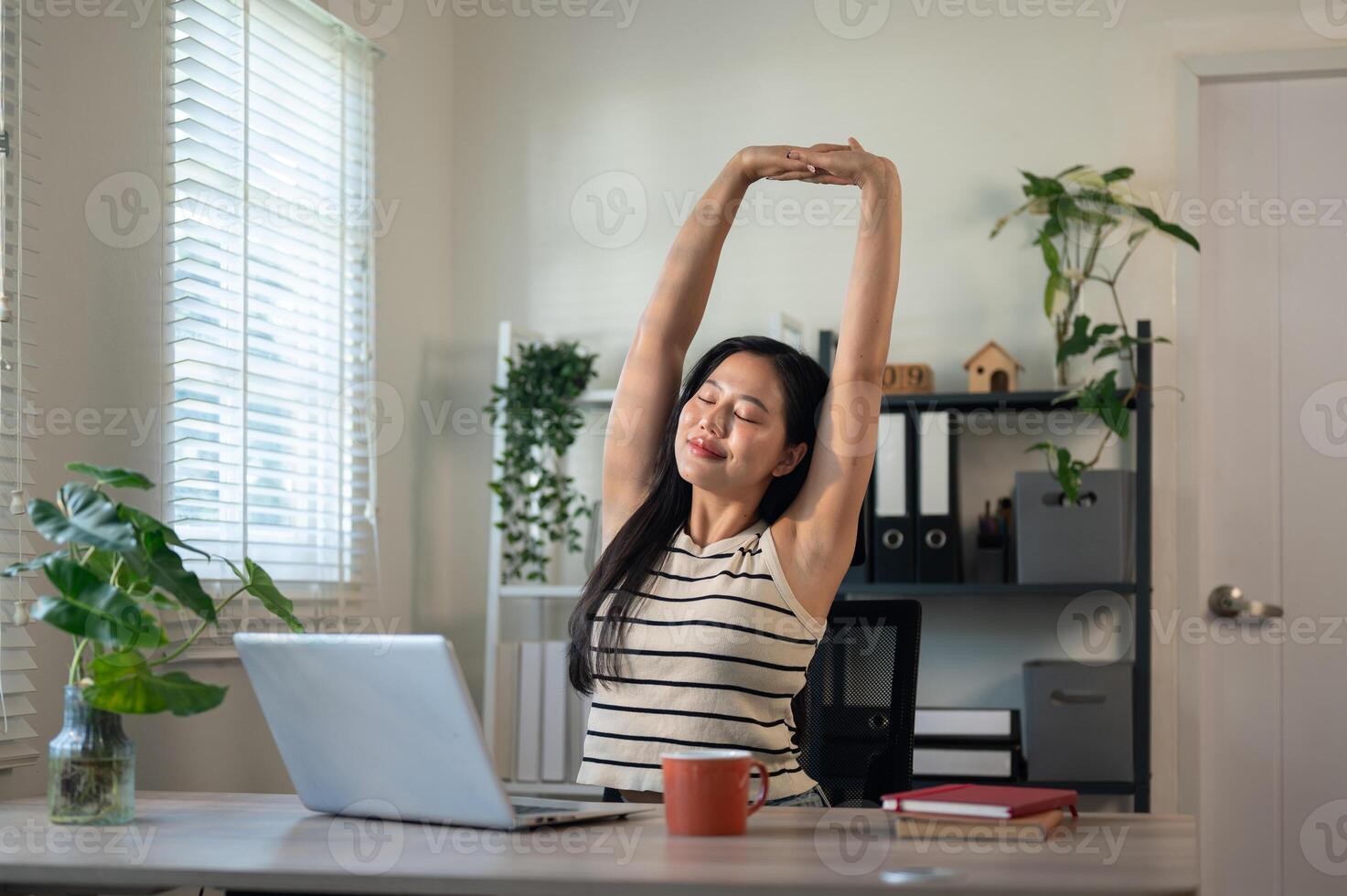 A carefree Asian businesswoman is stretching her arms to relax after finishing her work on a laptop. photo