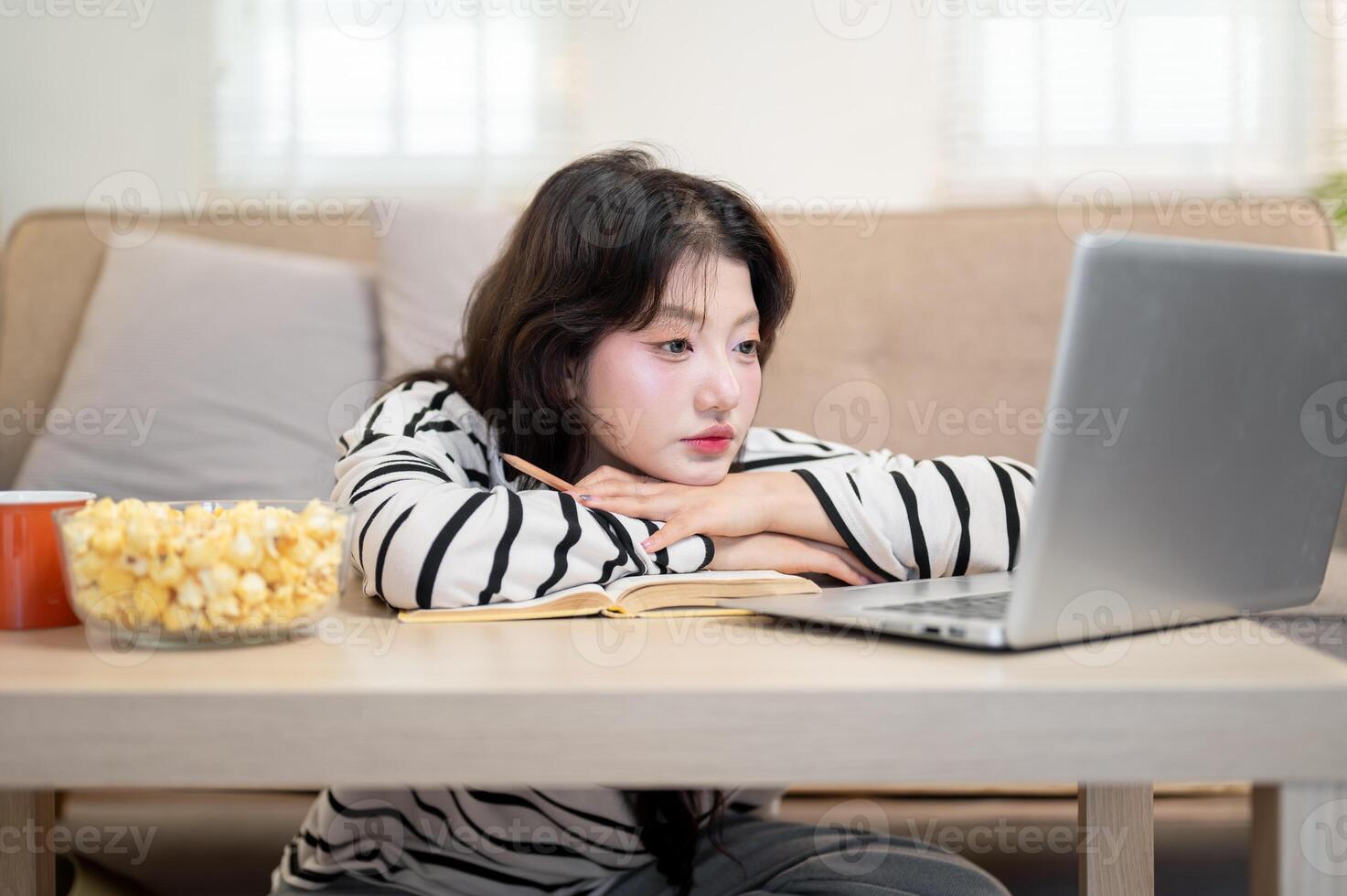 A tired Asian female university student is feeling bored from her online lecture, studying at home. photo