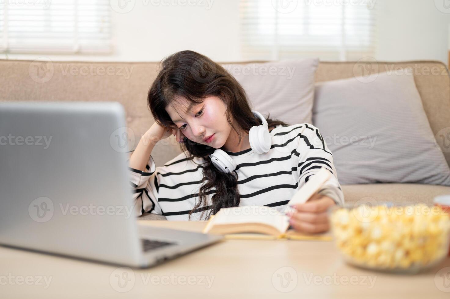 A tired young Asian female university student is feeling bored and exhausted from her online lecture photo