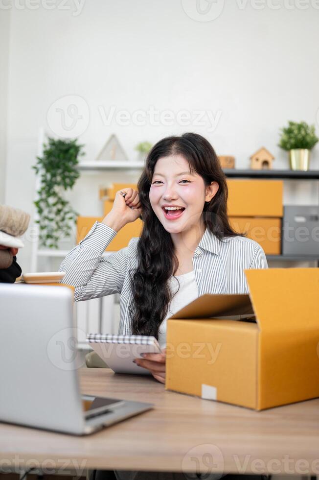 A cheerful Asian female online shop owner is smiling at the camera and showing a triumphant fist. photo