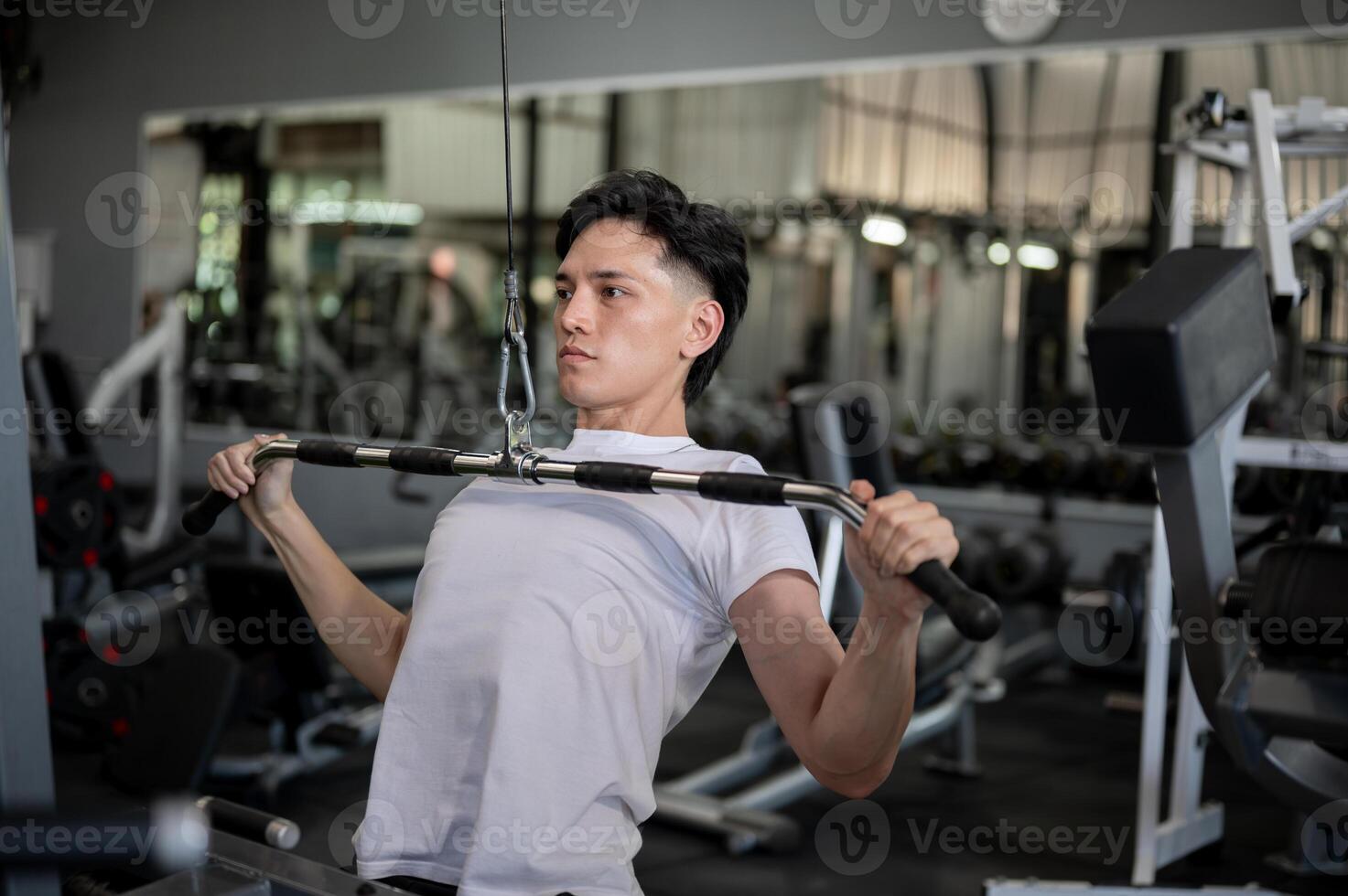 A strong Asian man is focused on working out with a cable machine in a professional gym. photo