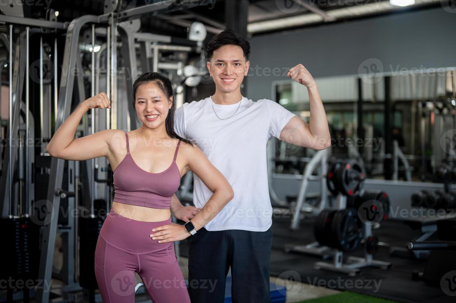 Two sporty Asians, a male and female are confidently showing a power gesture with their arms. photo