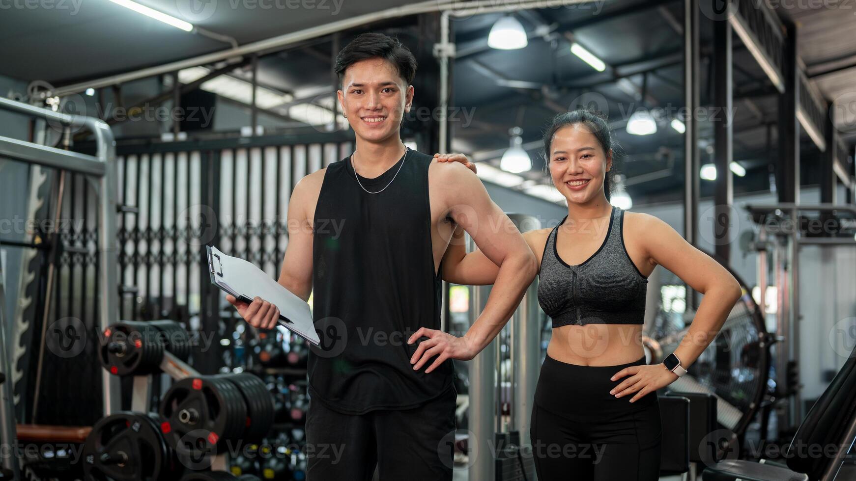 Two professional, confident Asian fitness instructors are standing in the gym. photo
