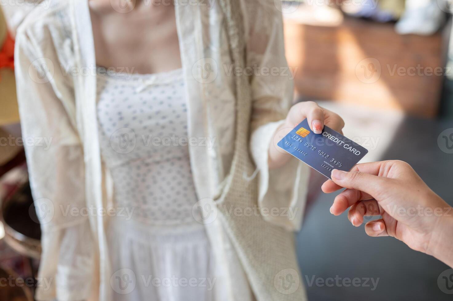 A close-up of a female customer handing her credit card to a shop cashier to pay for her items. photo