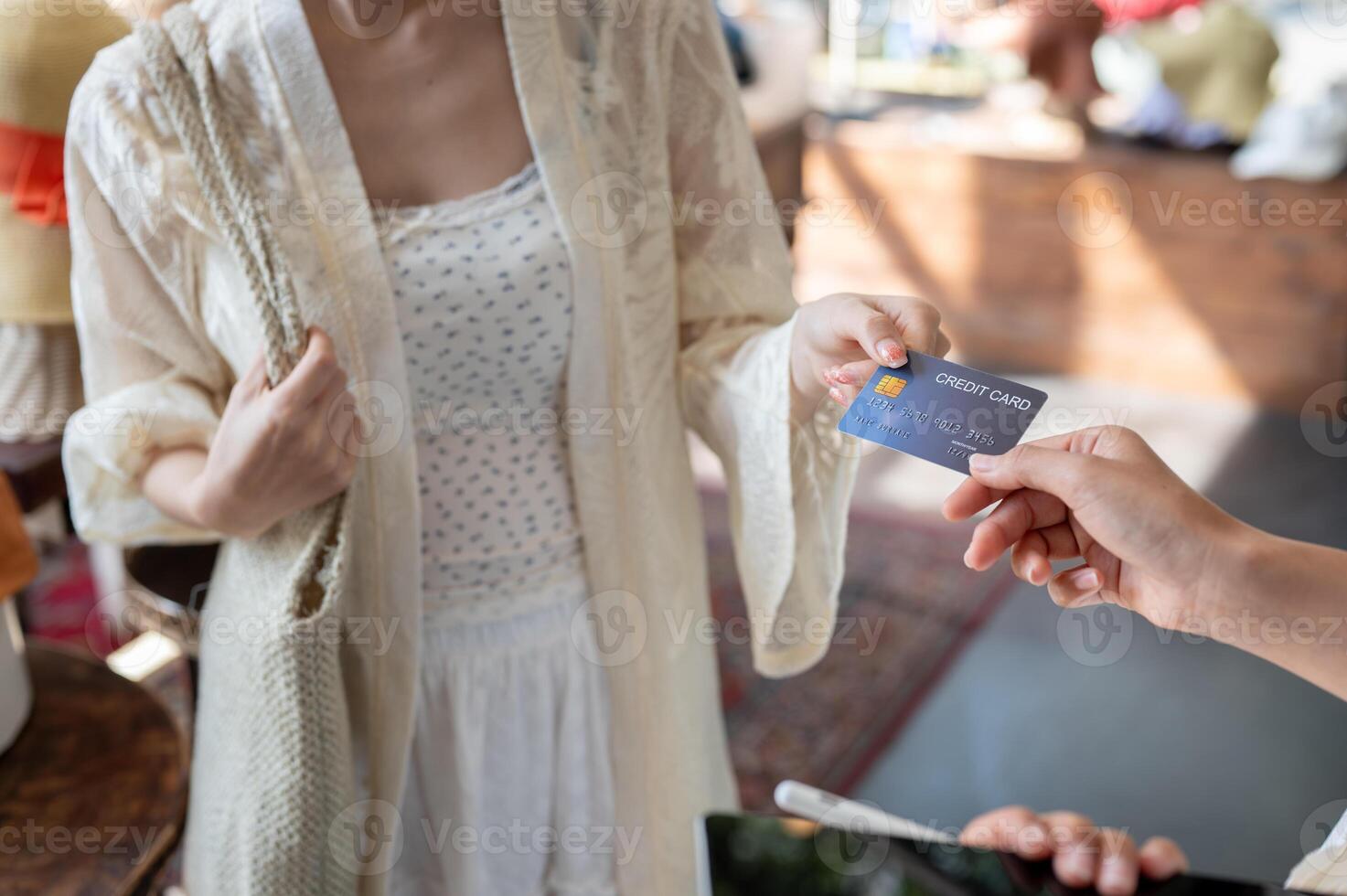 A customer handing her credit card to a shop cashier to pay for her items while shopping at a store. photo