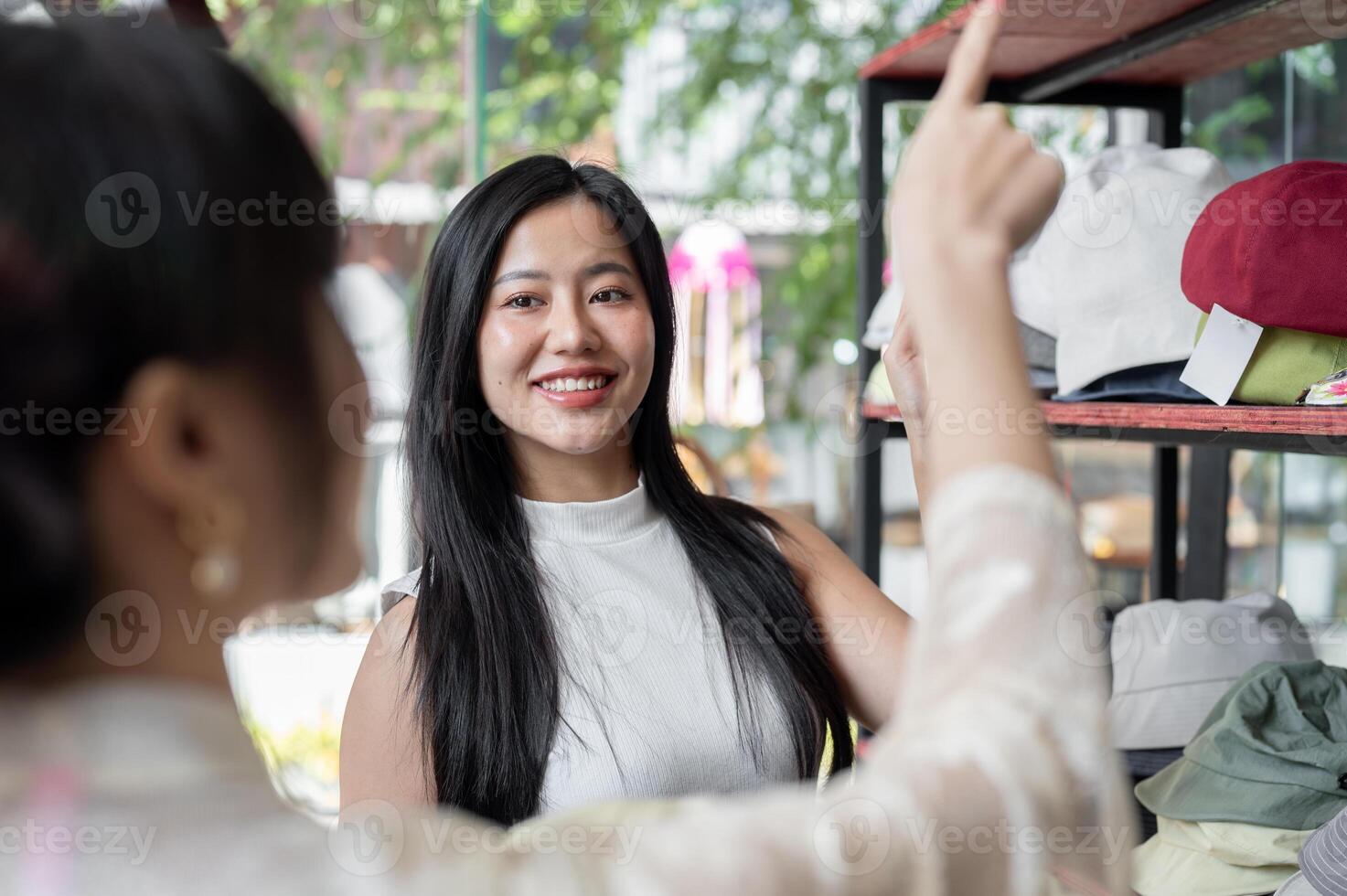A customer is pointing at the item on the shelf she wants to buy, showing it to a store employee. photo