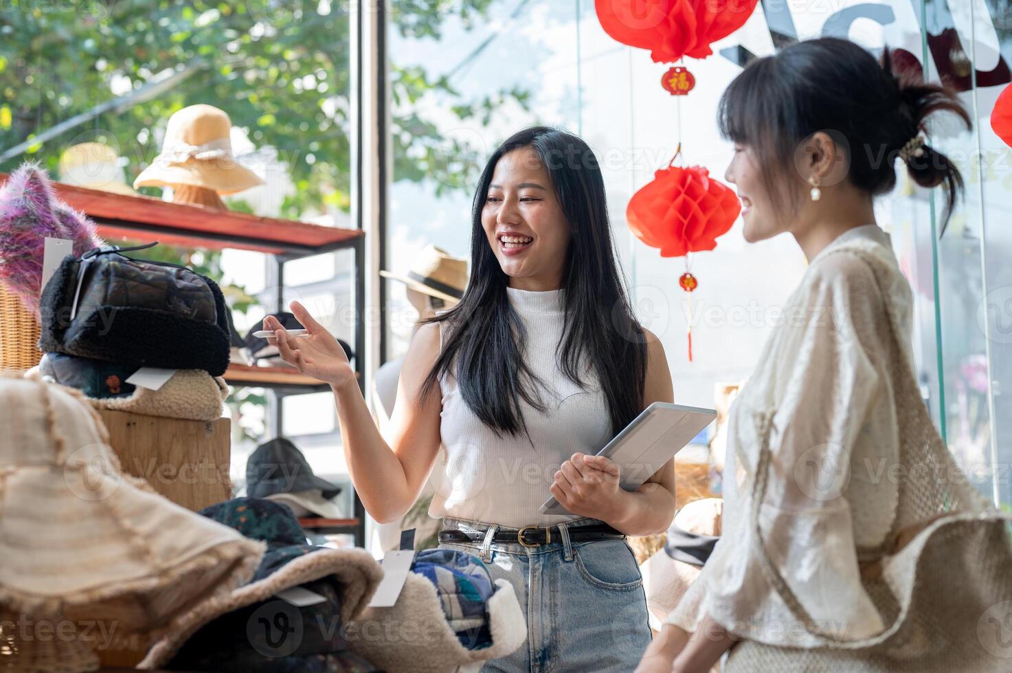 A service-minded Asian female shop employee or manager is recommending new items to a customer, helping them select items from her shop. photo