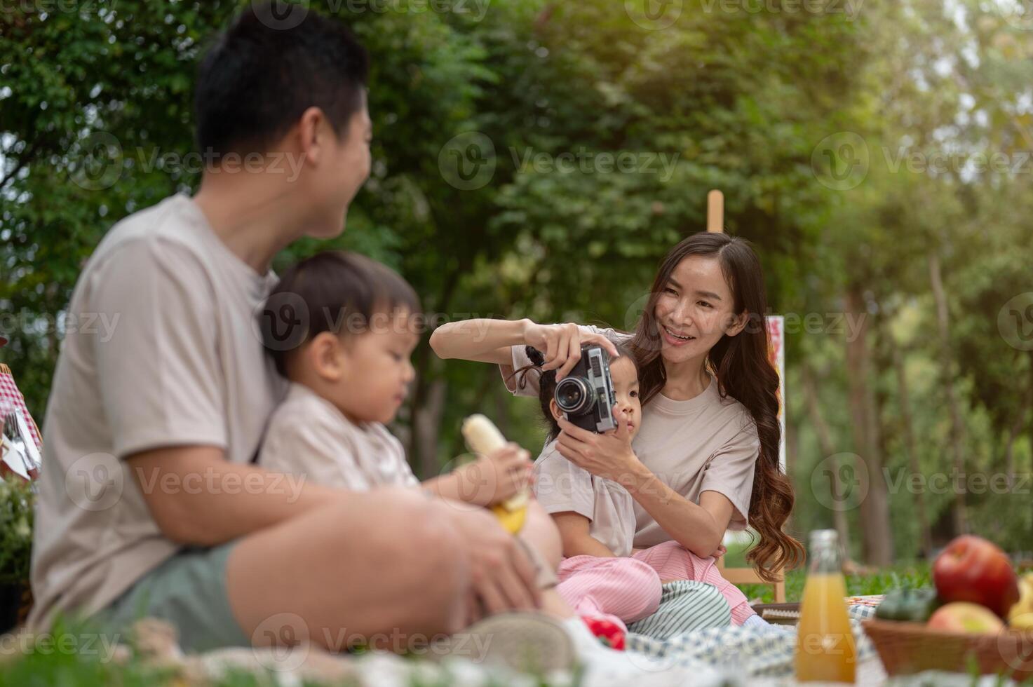 A cheerful Asian mom enjoys picnicking with her family in a public park. photo