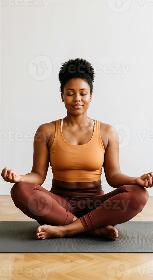 Young African American woman practicing yoga meditation in brown activewear photo
