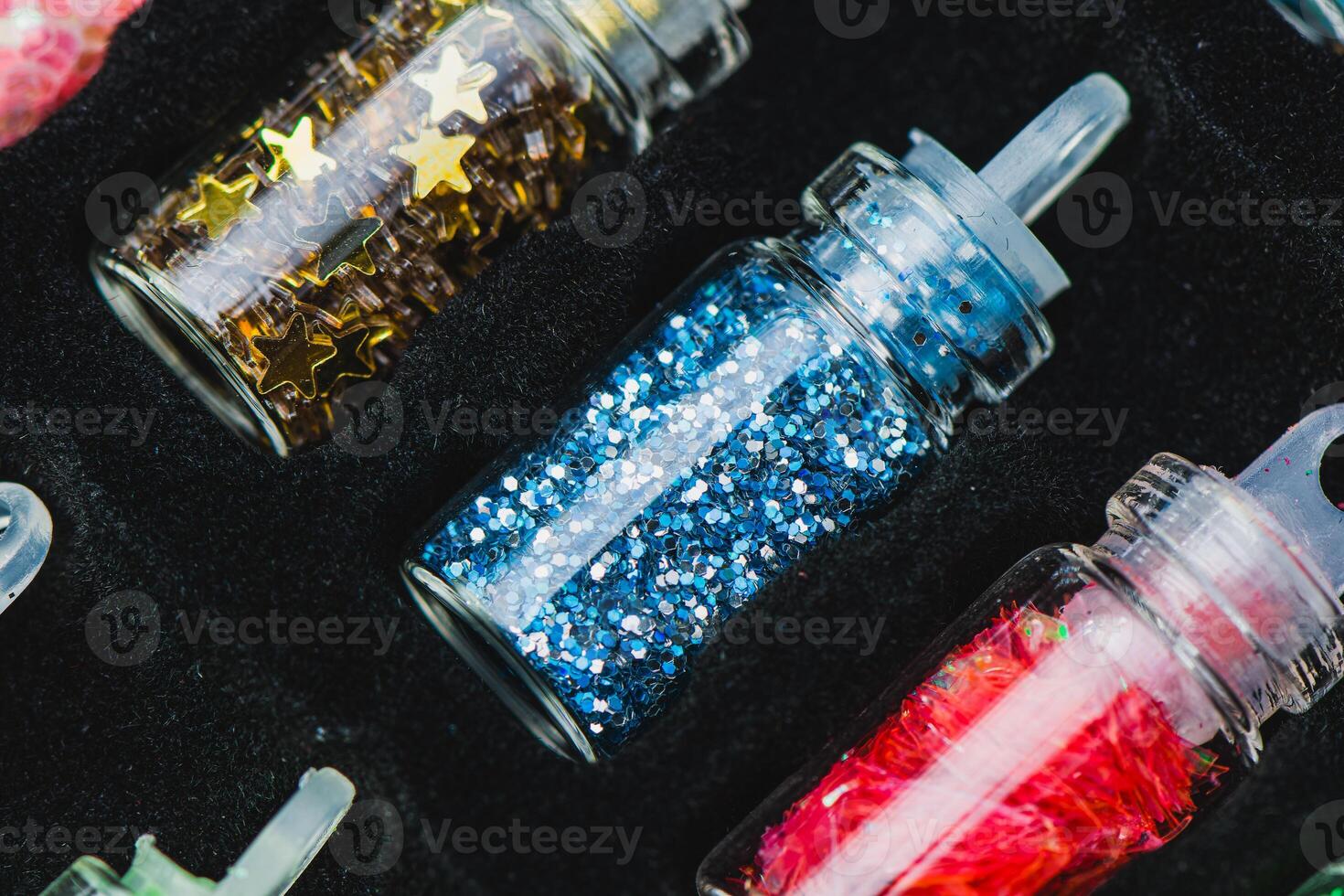 Glass Bottles with Different Types of Glitter, Gold Star-Shaped Glitter, Blue Glitter, and Red Shredded Glitter in a Black Foam Holder. Ideal for Crafting and Decorative Projects photo