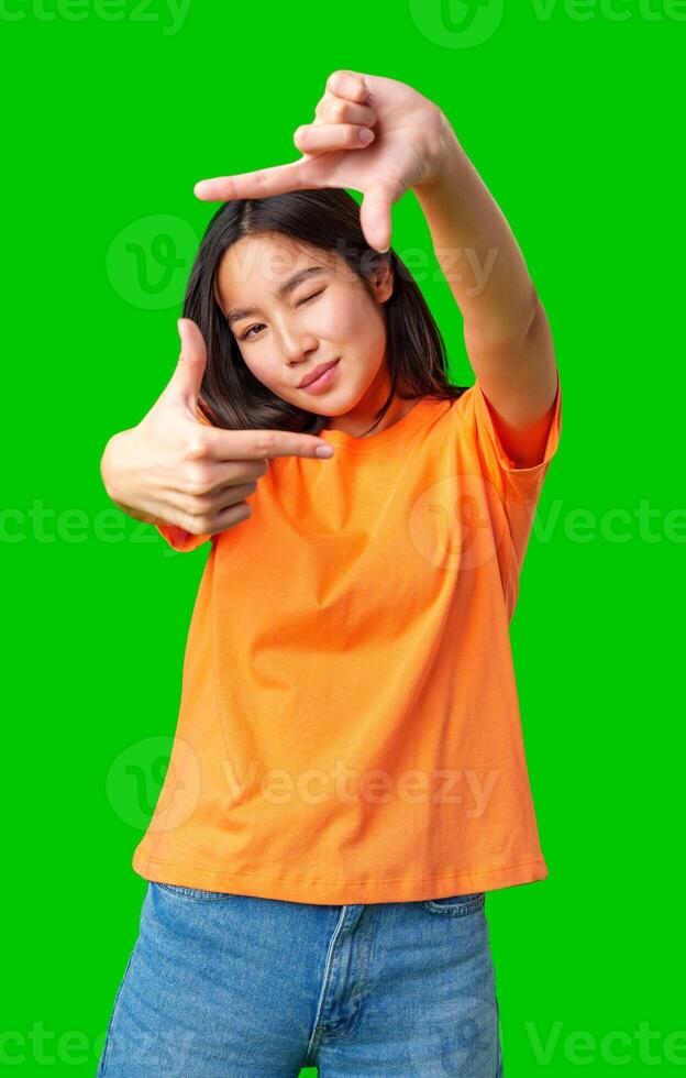 Young woman poses playfully with hand gestures against a bright green background in a casual setting photo