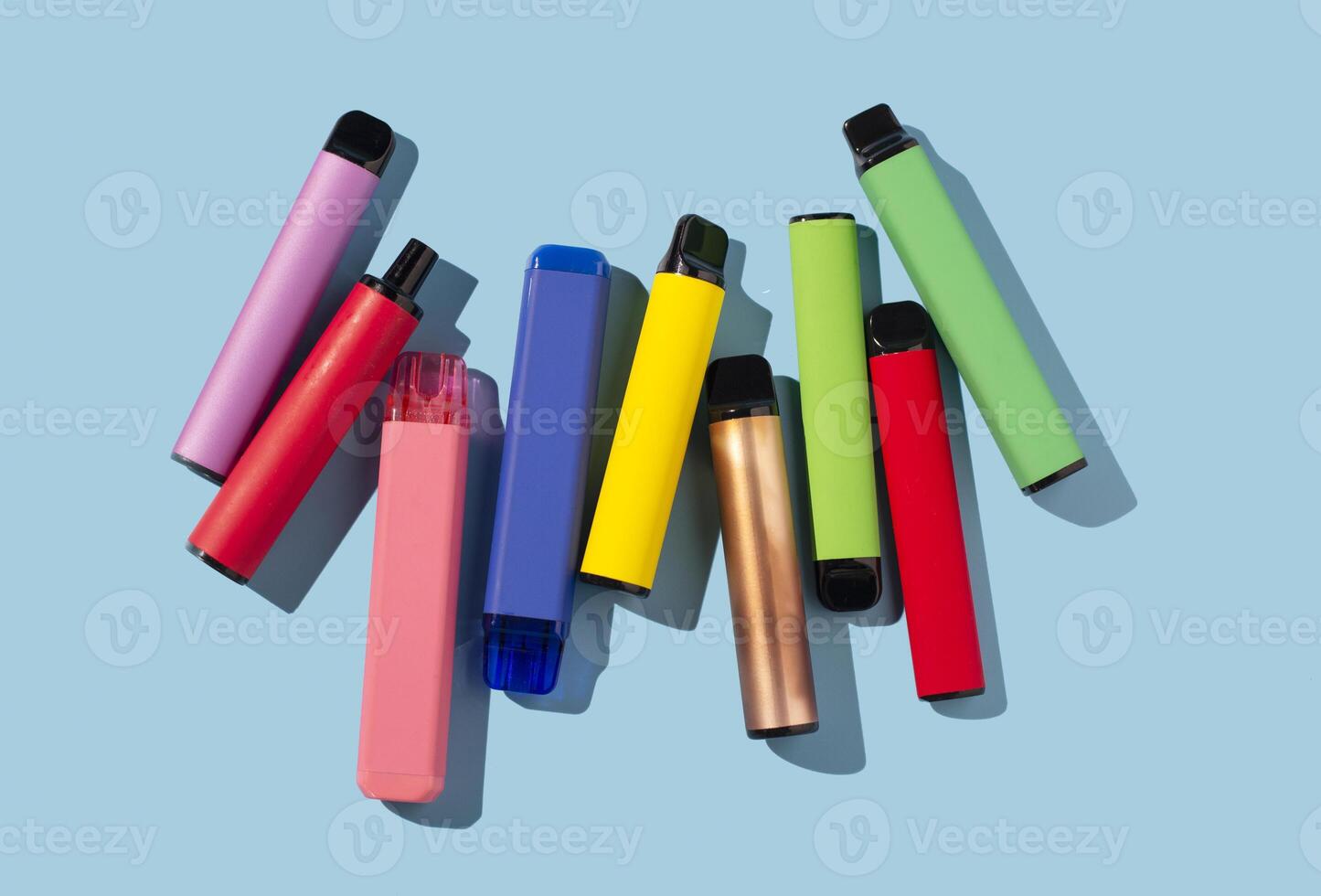 Set of colorful disposable electronic cigarettes on a blue background. The concept of modern smoking photo