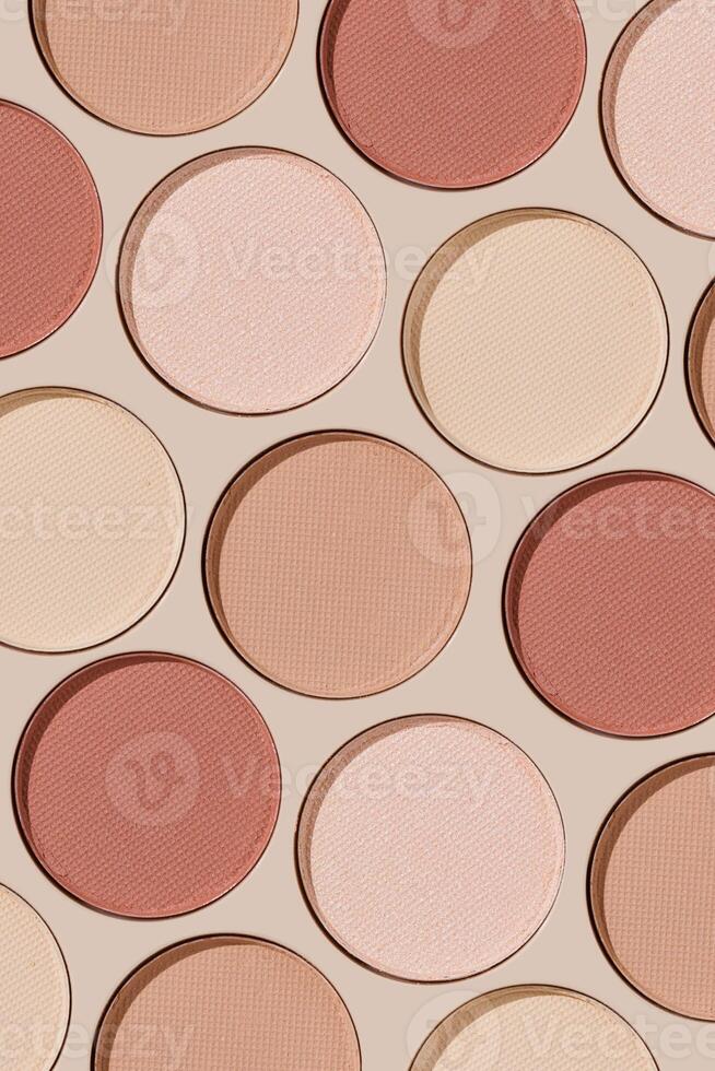 Eyeshadow palette, mix of matte and shimmer shades in pink, nude, red, brown hues. Minimal top view pattern for beauty, makeup, cosmetics themes, Pastel color swatches eyeshade refills round shape photo