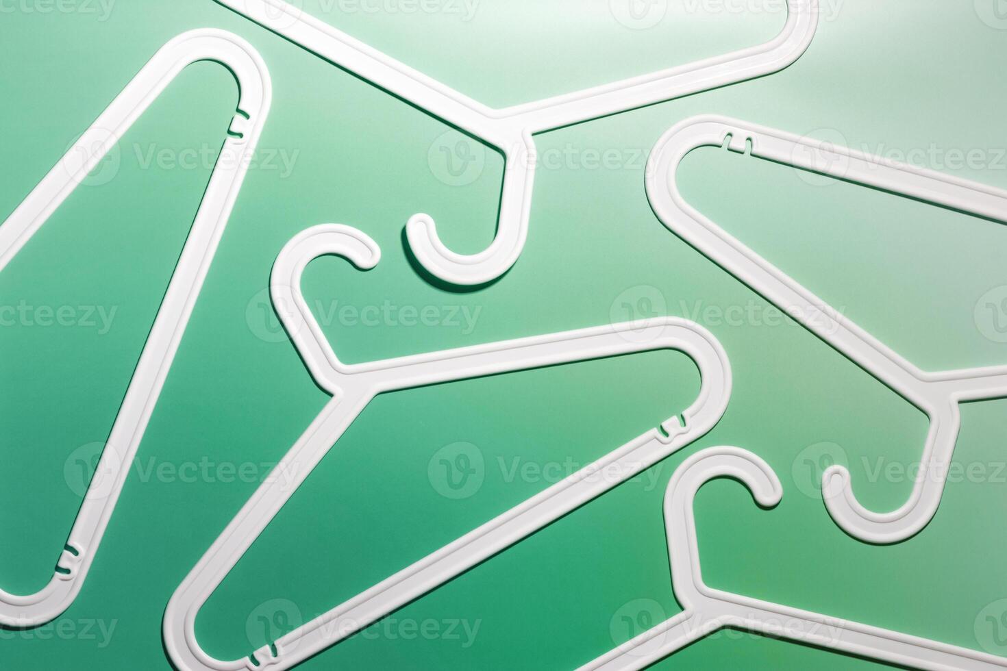 Top view minimal style pattern of white plastic hangers with hooks on white green background. Flat lay with Clothes rack for hanging garments. Minimal trend photo, lifestyle or interior design concept photo
