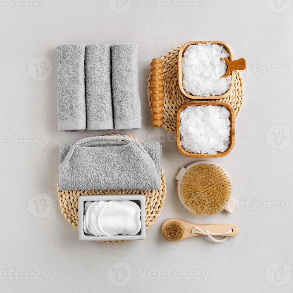 Spa, wellness, bath products as minimal style aesthetic pattern, magnesium salt flakes, folded grey towels, natural brushes, massagers, reusable pads, gray background, top view lifestyle content photo