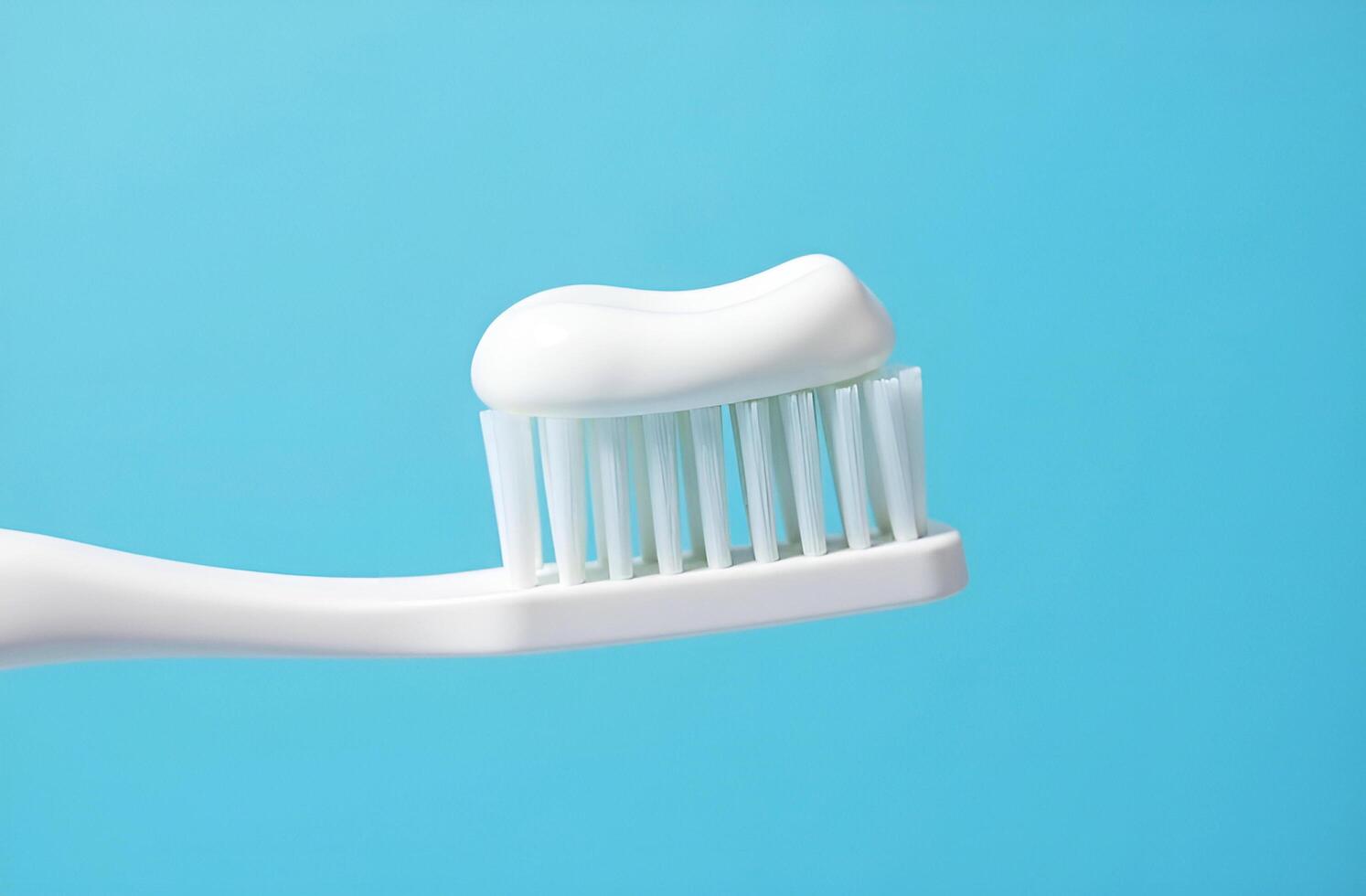 White toothbrush with some white toothpaste on blue background photo